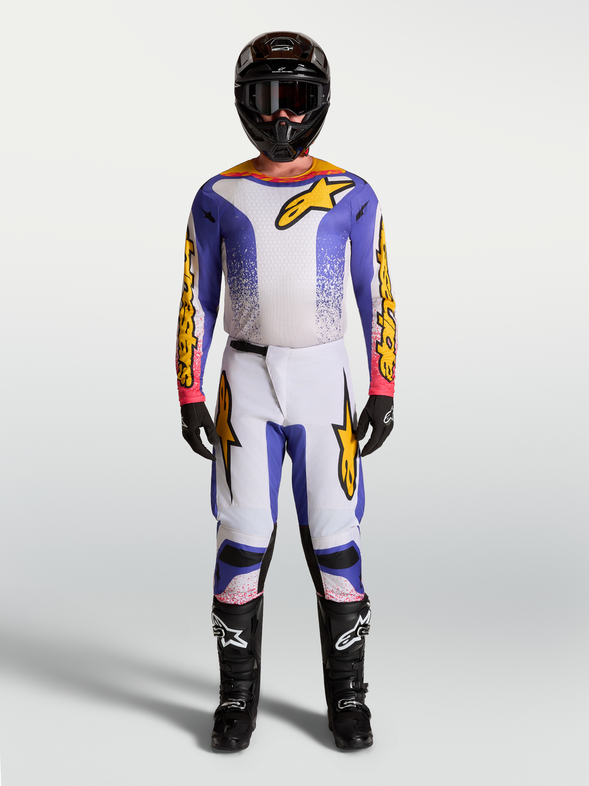 Alpinestars Fluid Drag, ensemble maillot et pantalon de motocross pour homme, bleu, lilas et doré, tenue tout-terrain haute performance portée par un mannequin avec casque et bottes