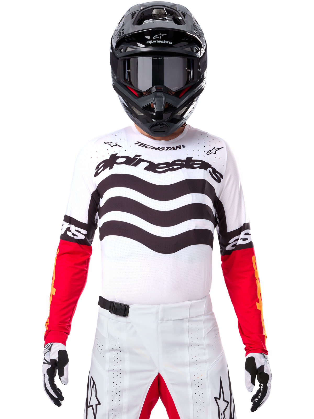 Pilote de motocross en tenue de course complète, Maillot Techstar Deep Édition Limitée blanc et noir avec manches rouges, graphismes ondulés et logo Alpinestars distinctif, pantalon de motocross blanc, casque et lunettes noirs, tenue coordonnée pour la course tout-terrain