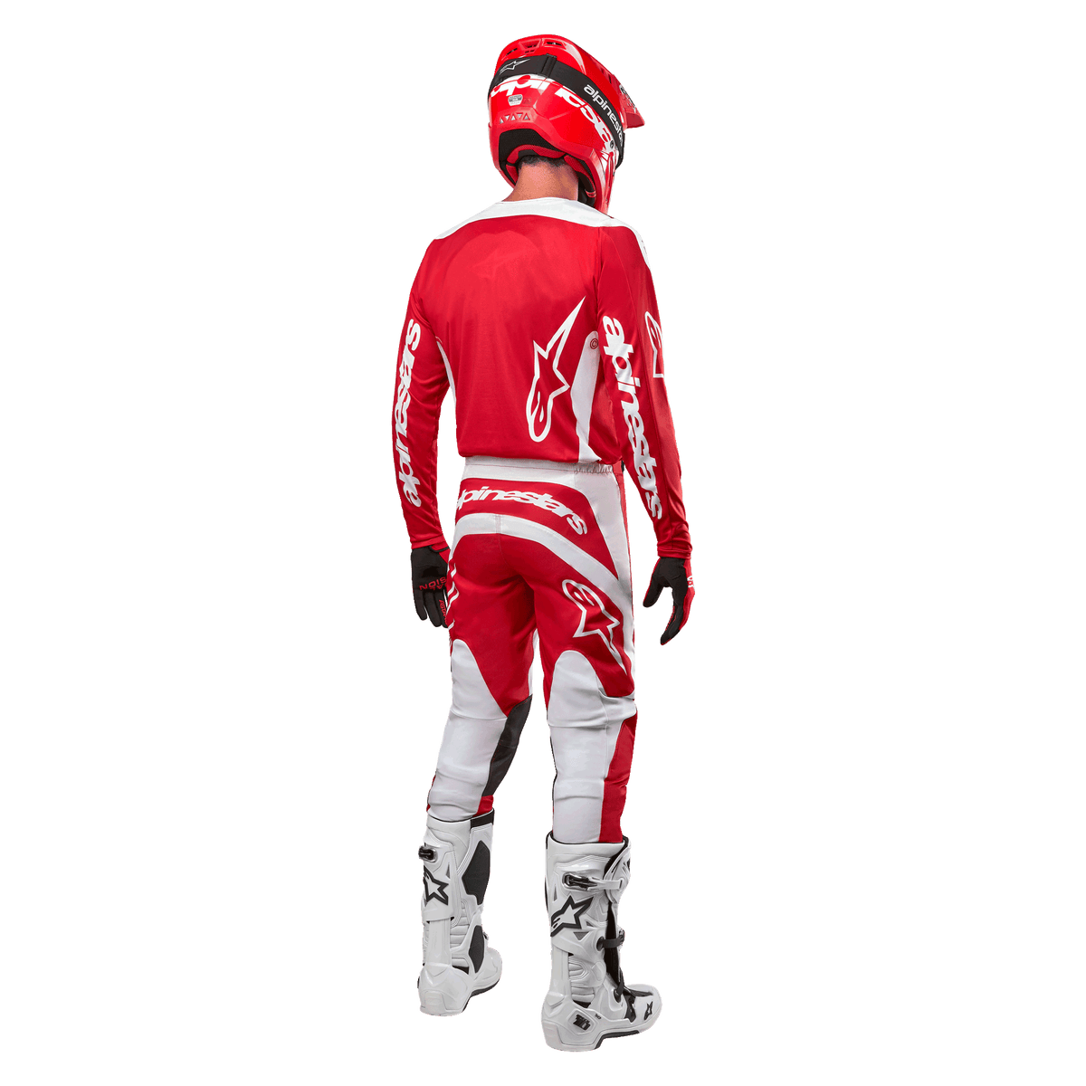 Vue arrière d'un pilote de motocross portant le maillot Alpinestars Fluid Lurv 2024 en Mars Red White, associé à un pantalon rouge et blanc assorti, des bottes tout-terrain blanches et un casque rouge, montrant le design arrière du maillot et le logo Alpinestars.