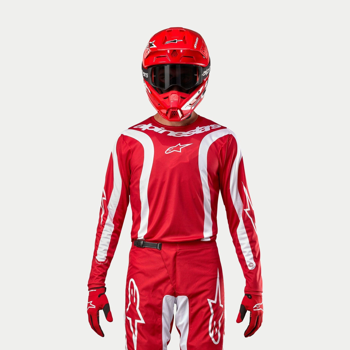 Alpinestars 2024 Fluid Lurv Jersey, maillot de motocross, rouge Mars et blanc, porté avec pantalon, casque et gants rouges assortis, avec des accents graphiques blancs sur les manches et un logo distinctif sur la poitrine, coupe athlétique pour la course tout-terrain
