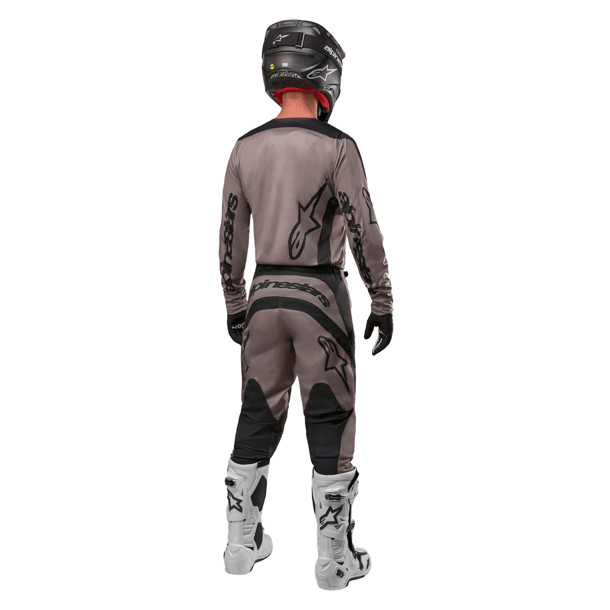 Maillot Alpinestars Fluid Lurv 2024, maillot de motocross, Mud Black, vue arrière d'un pilote de motocross portant une tenue de course assortie, casque noir et bottes blanches, avec logos Alpinestars noirs et coupe athlétique pour la performance tout-terrain
