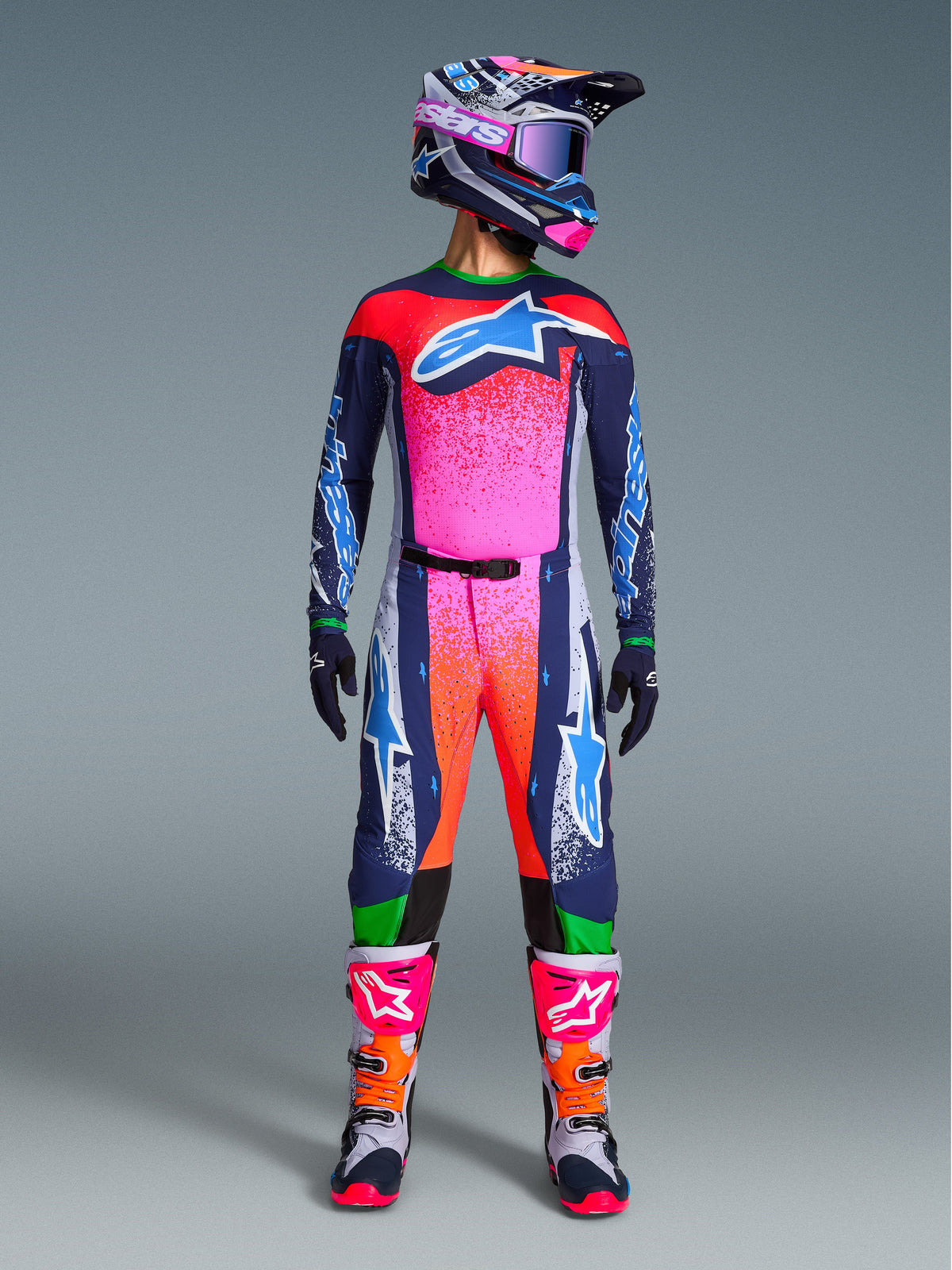 Alpinestars Limited Edition Supertech Records Gear Set, full motocross racing outfit featuring navy blue jersey and pants with vibrant pink and orange splatter patterns, matching helmet, purple goggles, and white boots with pink accents, professional athletic-fit gear for off-road performance