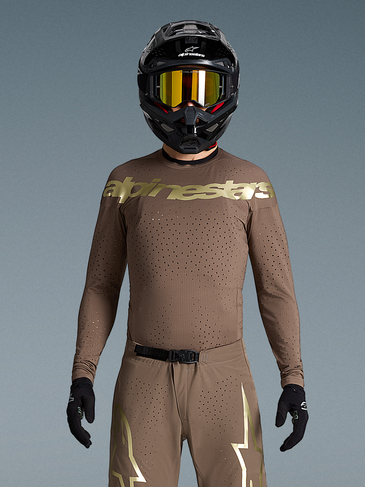 Tenue Alpinestars Supertech Air Gold édition limitée, motocross homme, marron et dorée, perforations laser et casque noir.