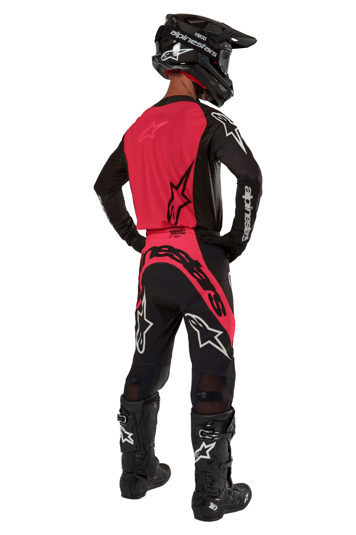 Motocross rider from behind wearing the 2024 Supertech Ward Jersey in Black Red Berry, featuring a vibrant red back panel and black sleeves with white Alpinestars branding. Paired with matching motocross pants, black Tech 10 boots, and a black carbon fiber helmet for a coordinated professional racing gear set.