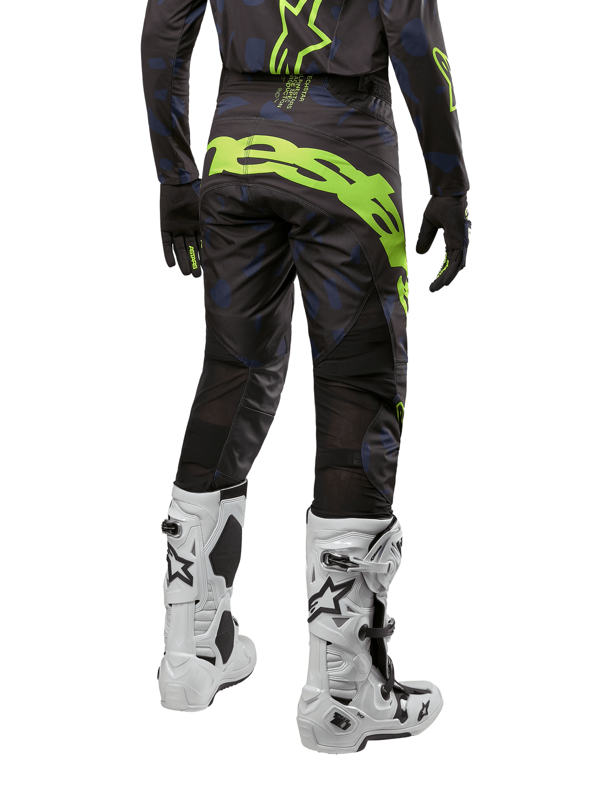 Pantalon Alpinestars 2024 Techstar Rantera, pantalon de motocross, noir, bleu marine et jaune fluo, vue arrière, avec logo jaune fluo audacieux et panneaux de ventilation en mesh, porté avec le maillot assorti et des bottes blanches, équipement durable pour le motocross et le tout-terrain