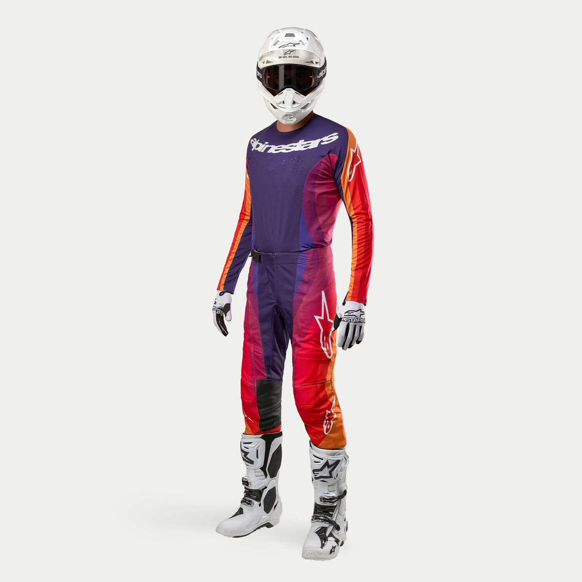 Tenue de motocross complète Alpinestars Techstar Pneuma 2024, casque blanc avec lunettes sombres, maillot et pantalon violet, orange et bleu foncé avec logos blancs, gants blancs et noirs, bottes blanches avec détails noirs, équipement de course coordonné