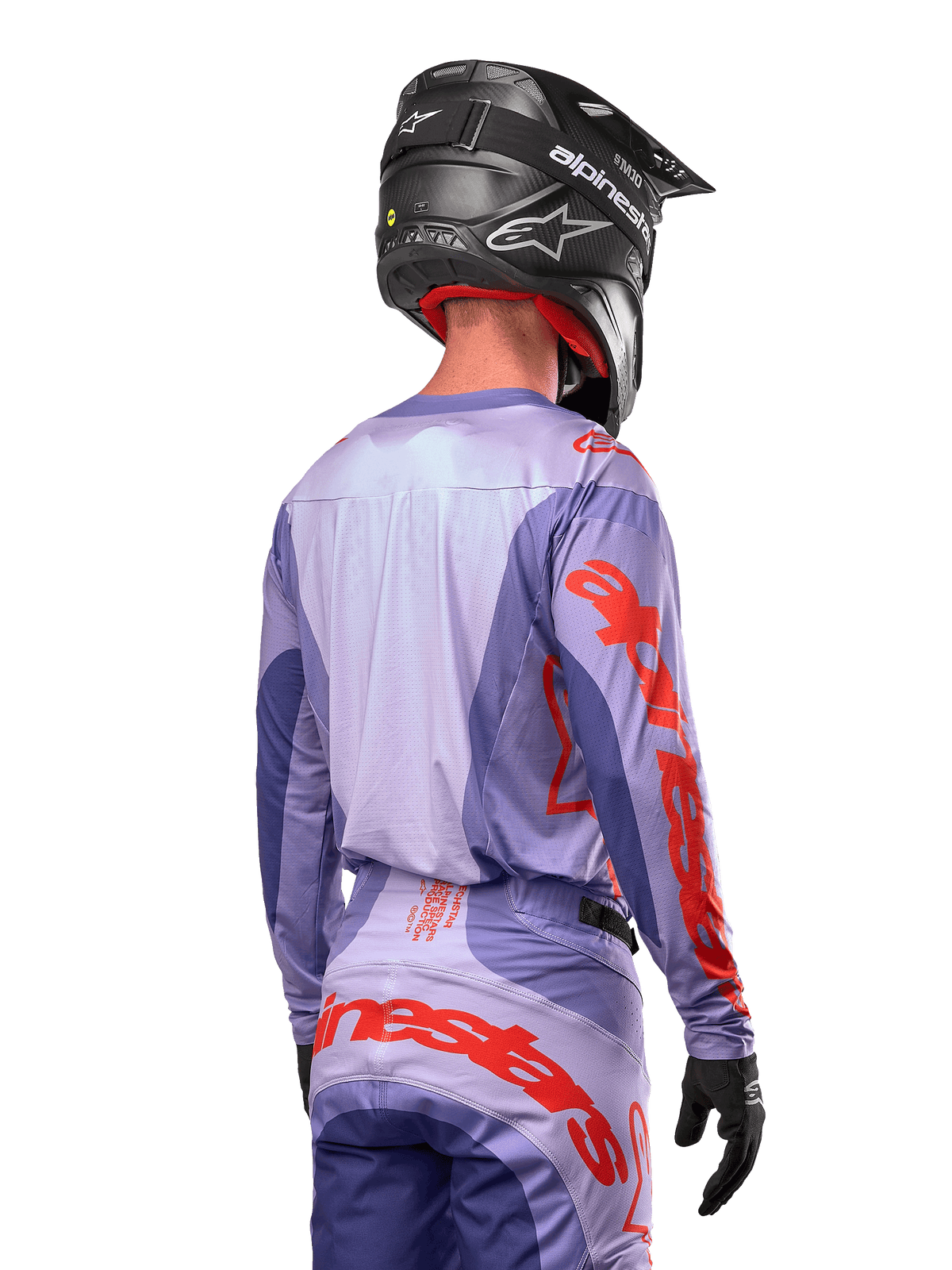 Maillot Alpinestars Techstar Ocuri 2024, maillot de motocross, pourpre et orange vif, vue arrière d'un pilote portant une tenue assortie et un casque noir, avec de grandes lettres Alpinestars orange sur les manches et le bas du dos