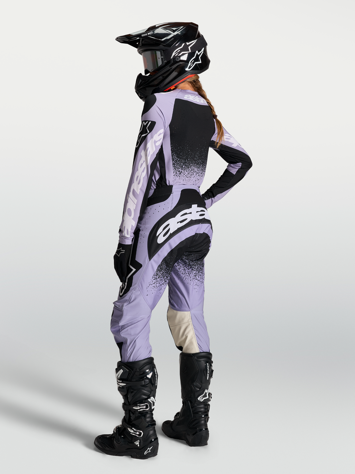 Maillot Stella Techstar Swan et ensemble Alpinestars pour femme, violet clair et noir, vue de dos avec casque et bottes.