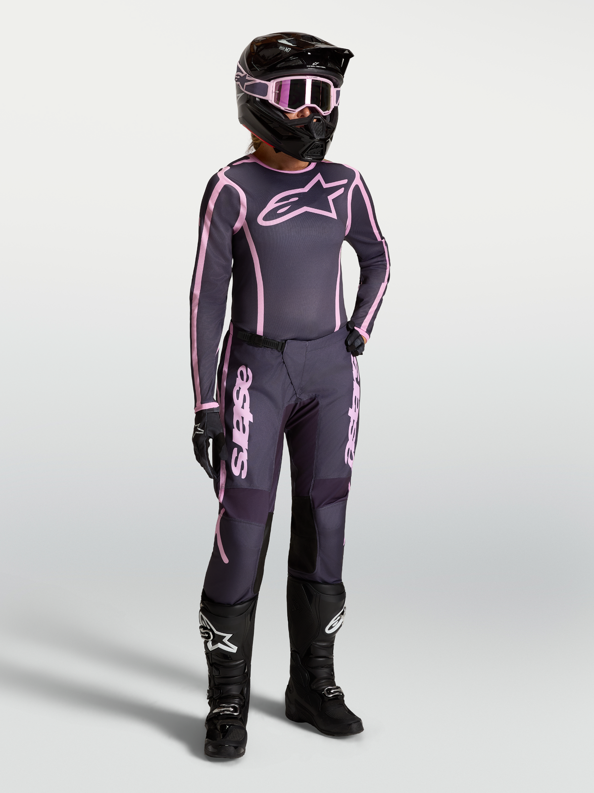 Maillot et ensemble Stella Fluid Apex V2 Alpinestars, tenue motocross pour femme, gris et rose, avec bottes de course noires.