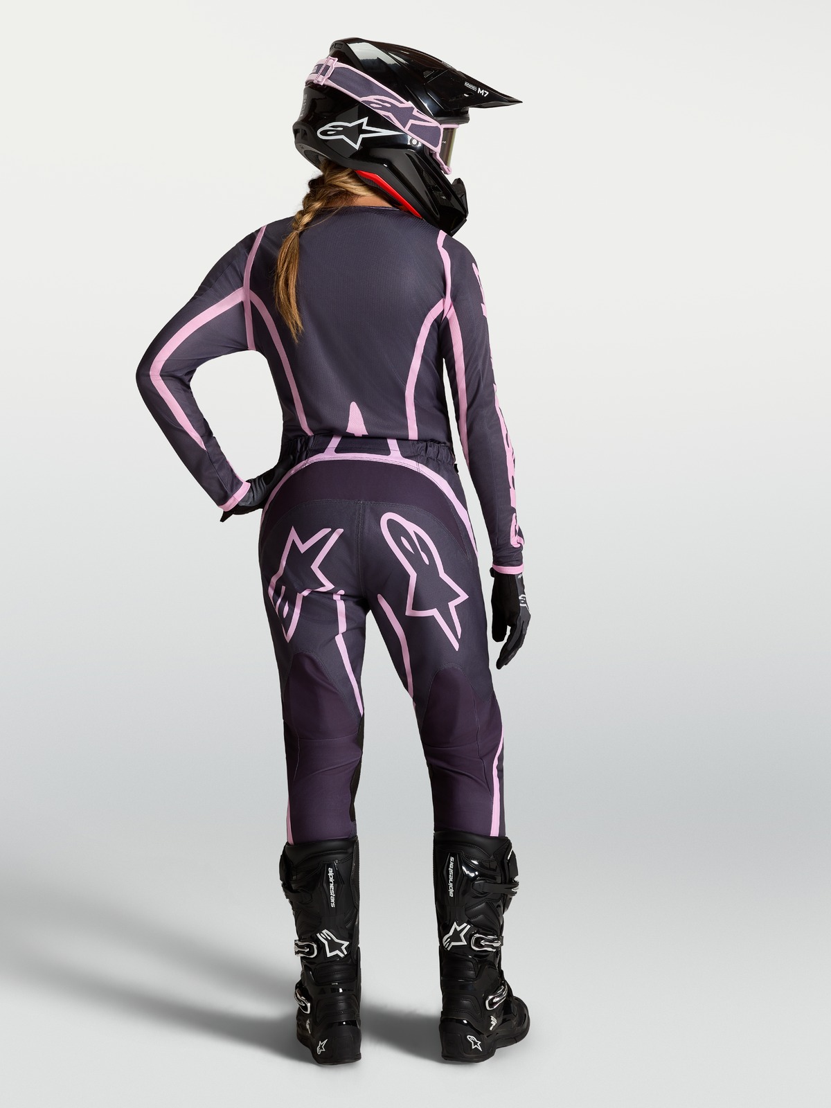Pantalons Alpinestars Stella Fluid Apex V2, équipement de motocross pour femme, gris et rose, vue de dos sur une pilote avec tenue assortie.