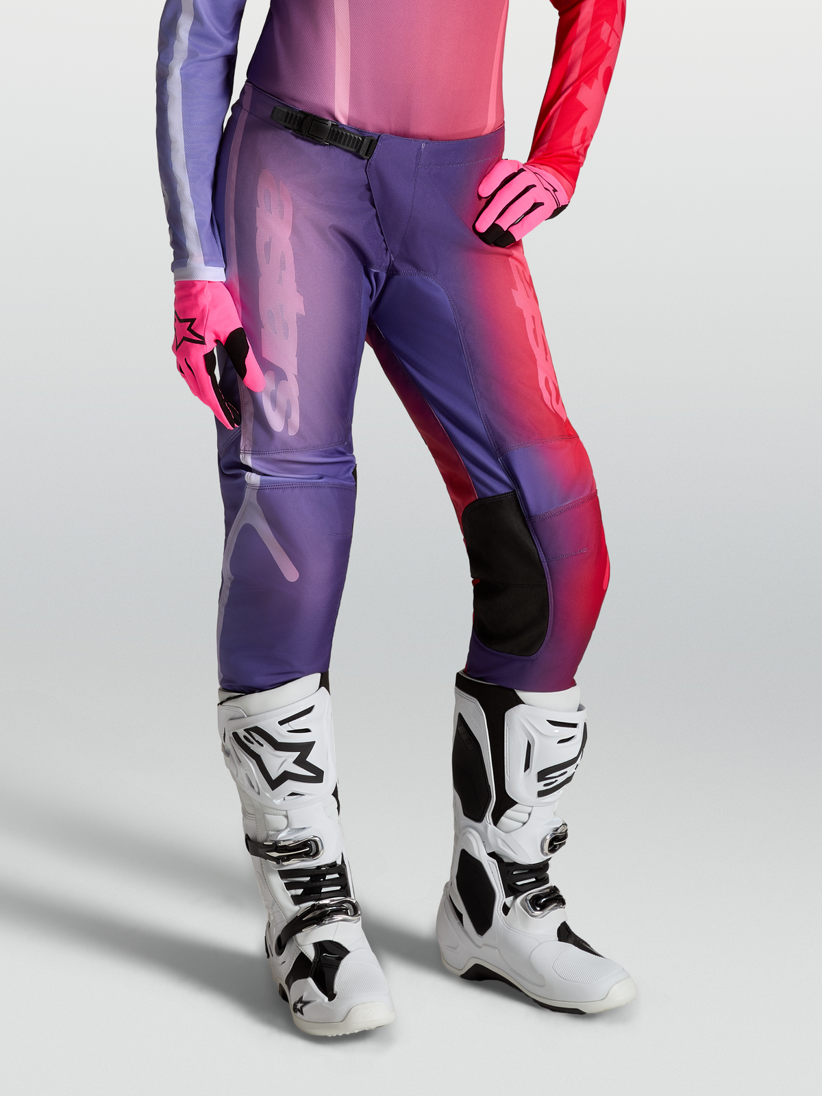 Alpinestars Stella Fluid Kepler, pantalon de motocross pour femme, violet et rouge, construction en poly-tissu 600D durable, porté avec gants roses et bottes blanches, équipement tout-terrain haute performance.