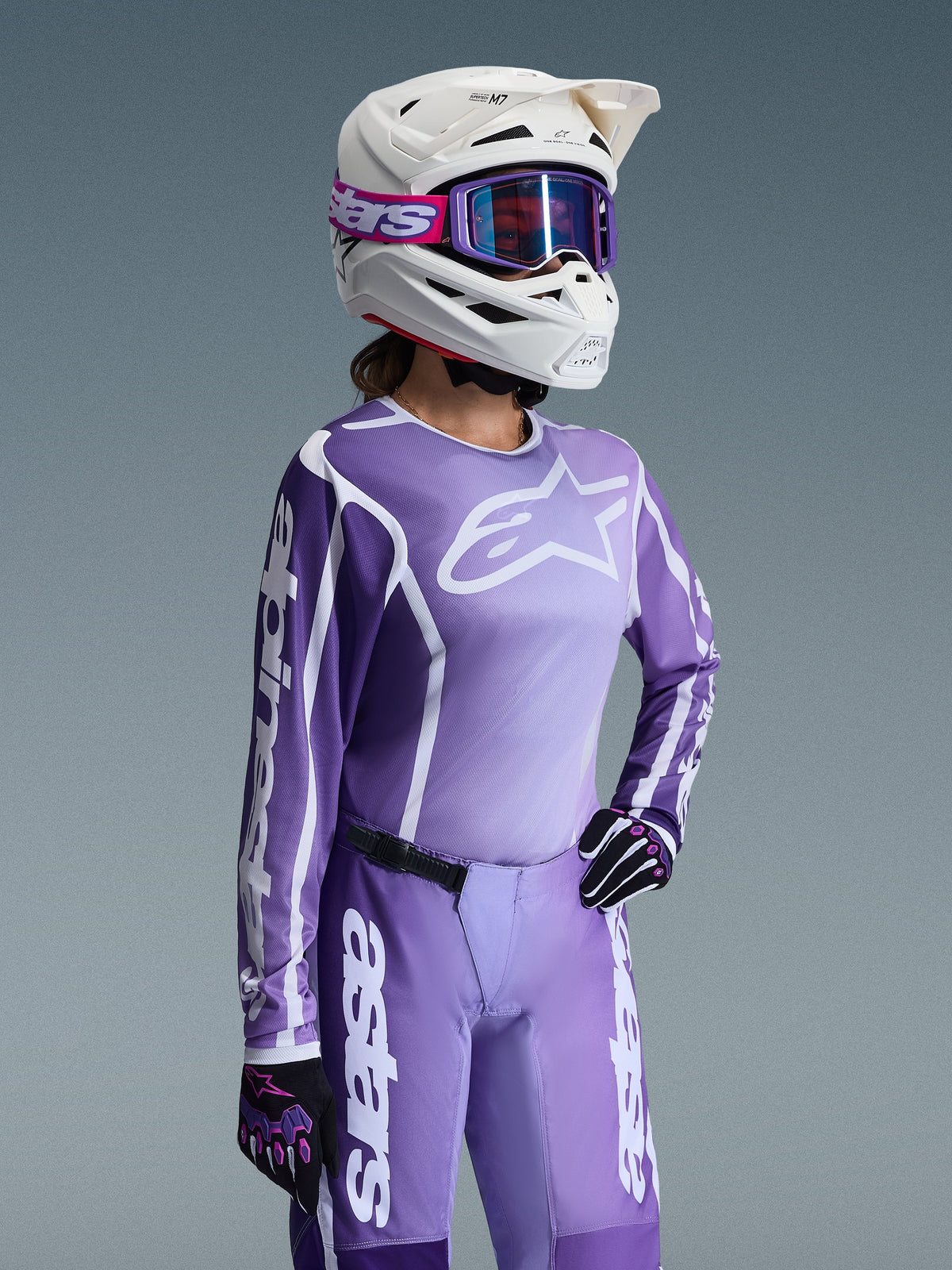 Alpinestars 2026 Woman Stella Fluid Apex Gear Set, Purple and lavender motocross jersey and pants, worn by a rider with a white helmet and purple goggles, featuring bold white Alpinestars branding and logos