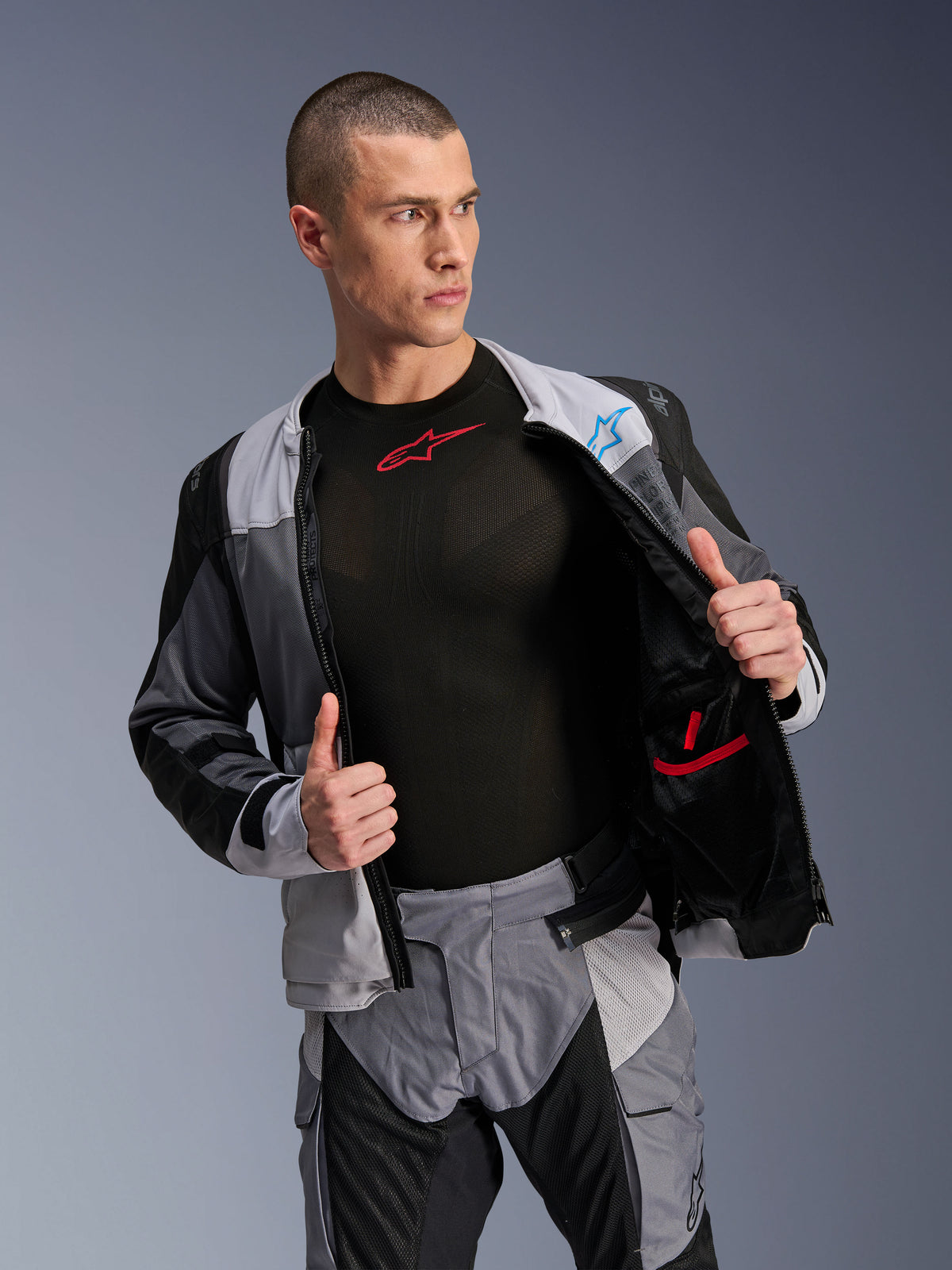 Veste Alpinestars ST-2 Air, Gris glacé, Gris foncé et Noir, veste de moto touring, portée ouverte pour montrer la doublure intérieure en mesh et les poches, associée à un pantalon assorti et une couche de base noire
