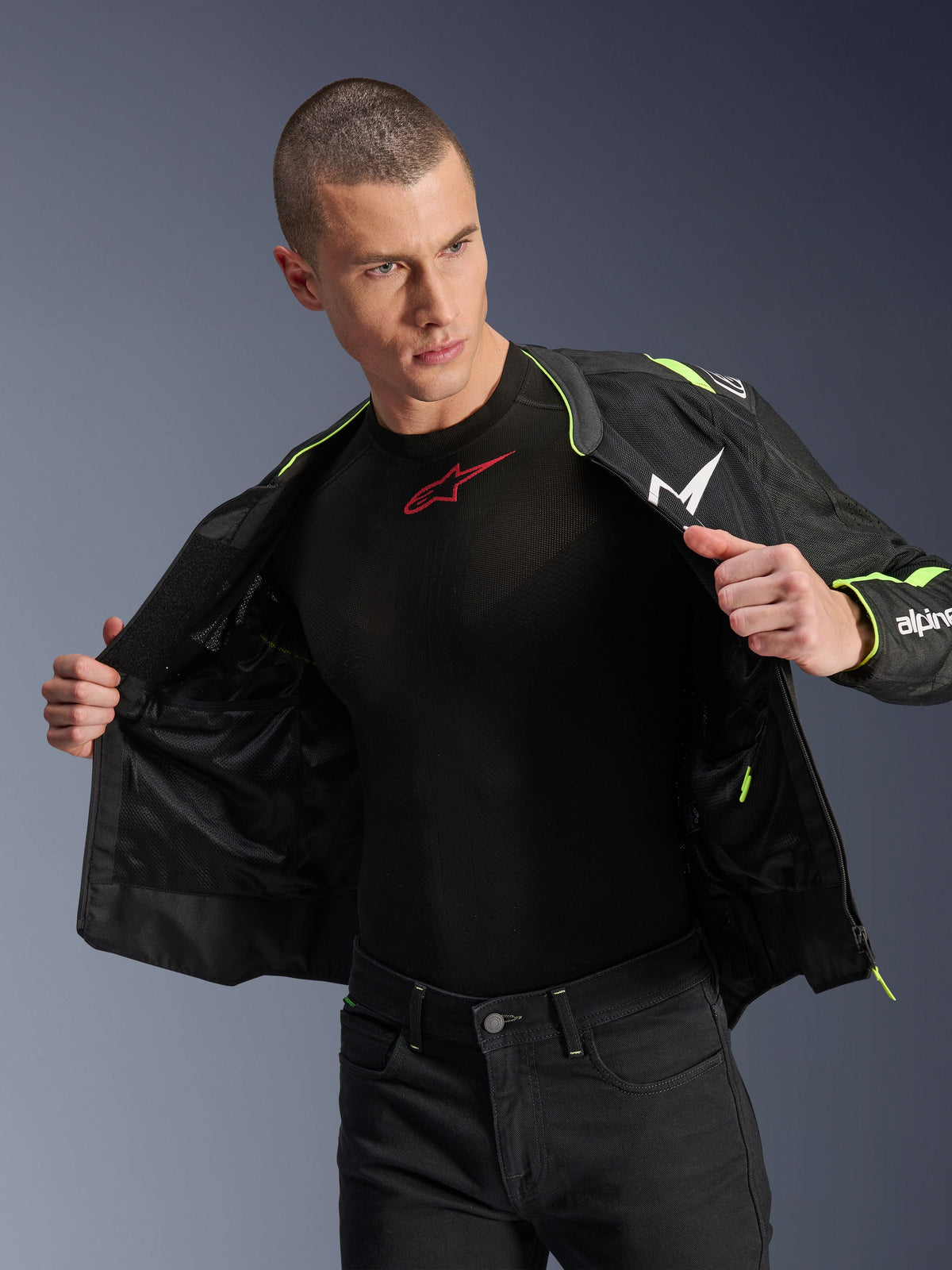 Mannequin homme portant la veste Alpinestars T-Sps Air V2 en noir et jaune fluo, présentée ouverte pour mettre en évidence la construction interne en mesh et les poches, associée à une couche de base Alpinestars noire et un pantalon noir, style d'équipement de moto urbain