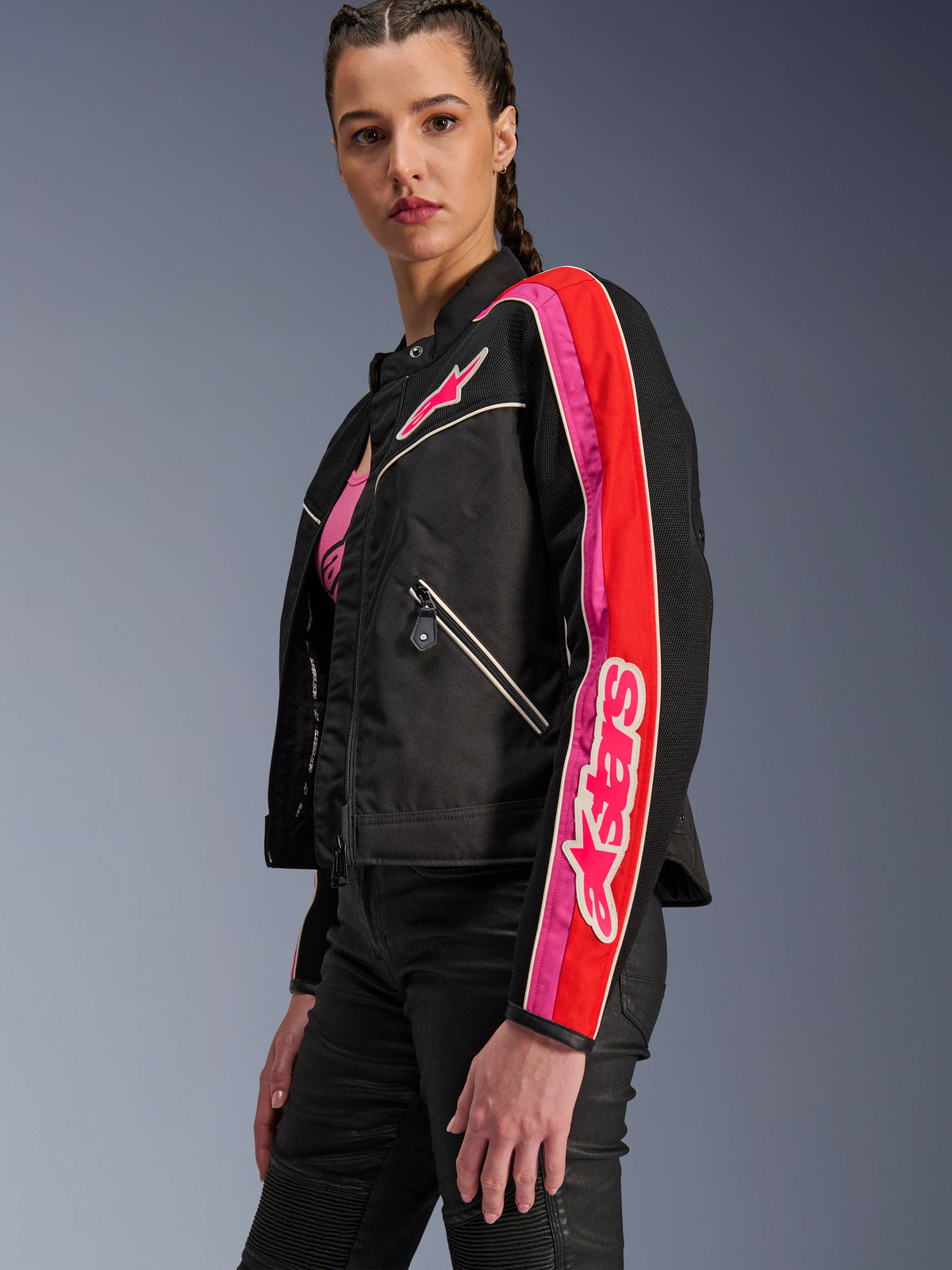 Alpinestars Woman Stella T-Dyno Air Jacket, Women's Motorcycle Jacket, Black with Bright Red and Fuchsia accents, worn with black pants, featuring pink Astars logo on the chest and sleeve, tailored biker fit with mesh panels for ventilation.