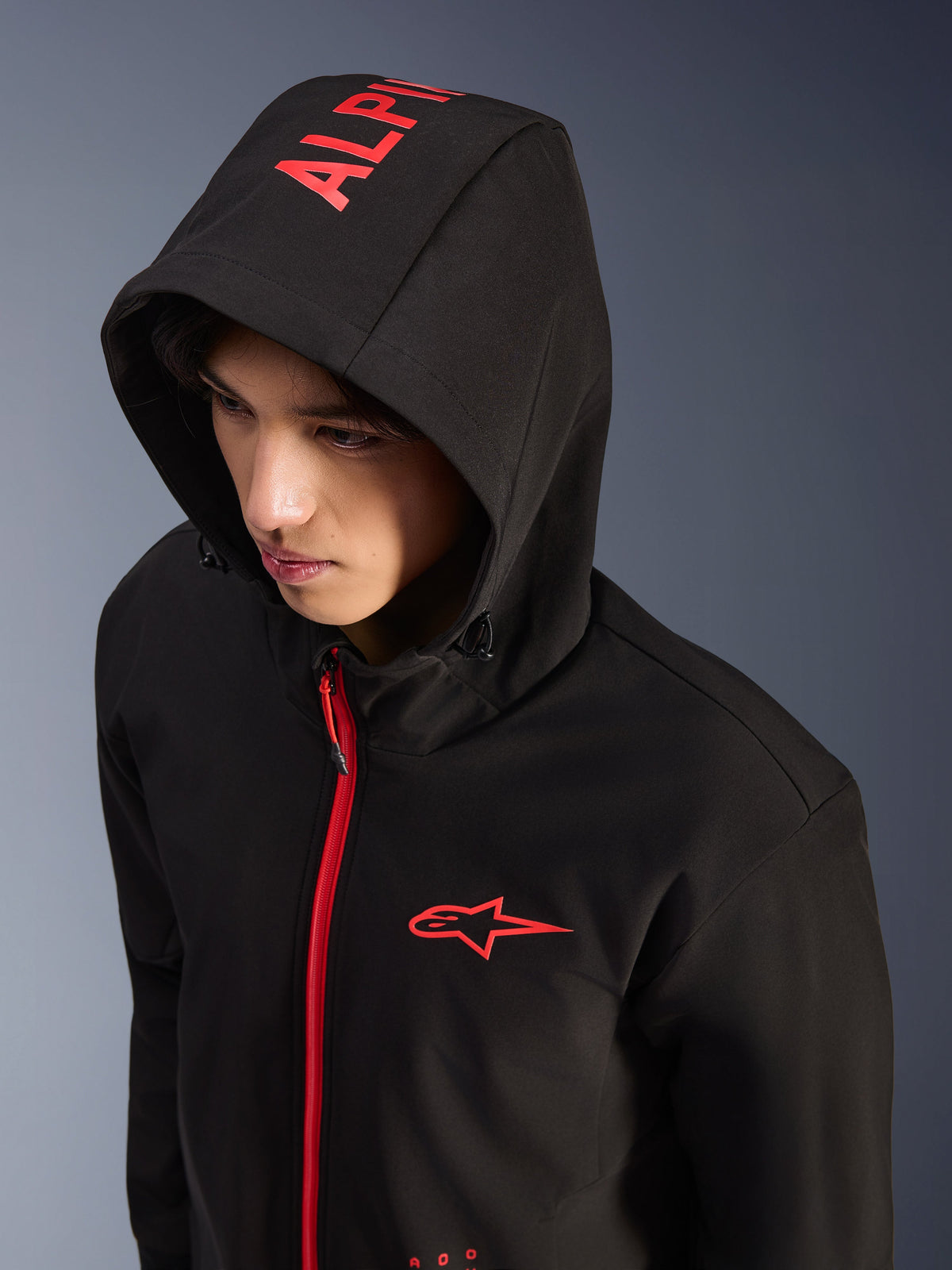 Alpinestars Radium Tech Hoodie, noir et rouge vif, sweat à capuche de moto technique urbain, logo Alpinestars rouge sur la poitrine et marquage rouge sur la capuche, fermeture éclair rouge vif, style streetwear moderne inspiré du sport automobile
