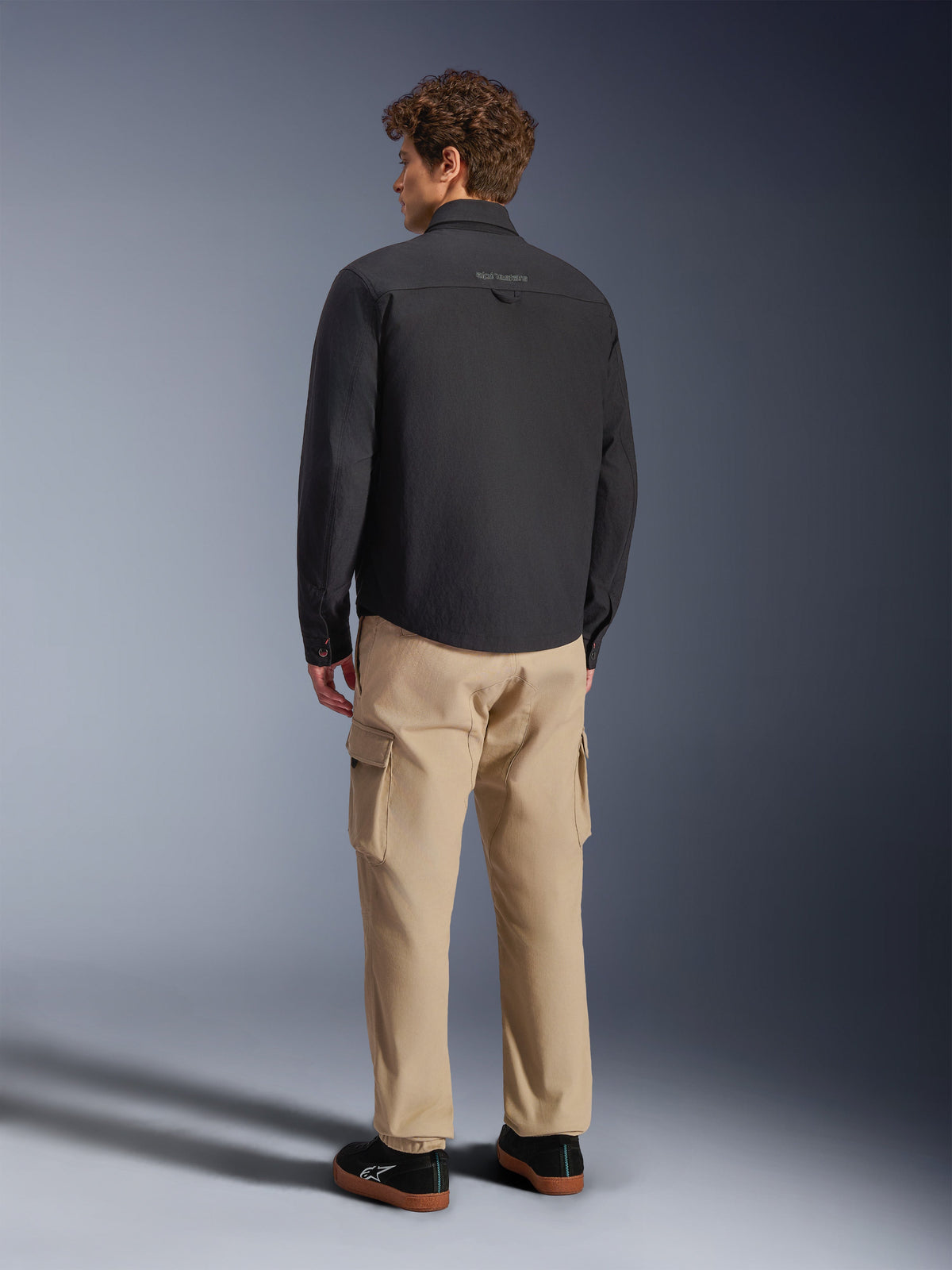 Alpinestars Bryon WR Overshirt, Black, rear view on model, paired with tan cargo pants and black sneakers, urban motorcycle jacket with waxed canvas texture and clean minimalist back design