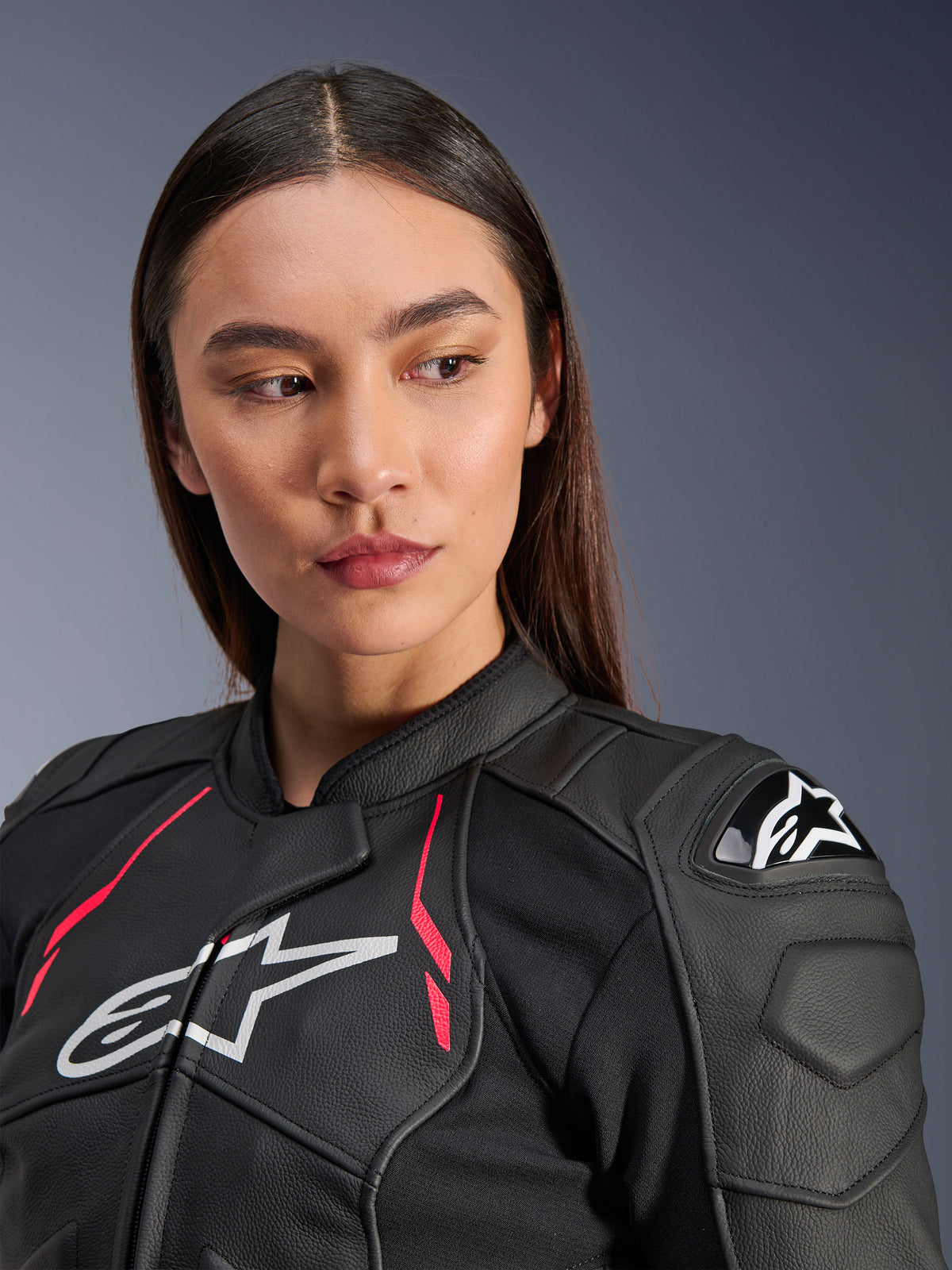 Femme portant la veste en cuir Alpinestars Stella Dusk en Black Diva Pink White, avec logo blanc sur la poitrine, accents rose vif et protections d'épaules externes DFS, équipement de moto en cuir bovin de qualité supérieure