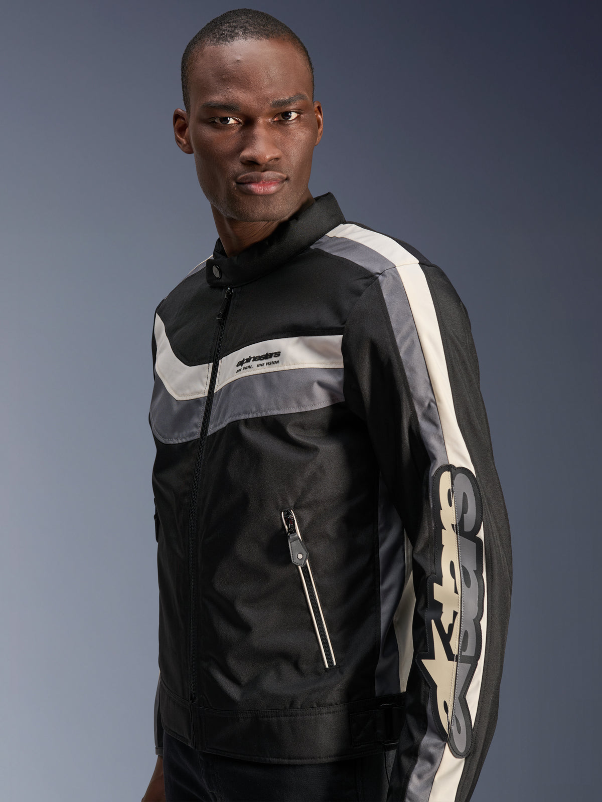 Veste Alpinestars T-Dyno WR, noir, gris foncé et écru, veste de moto en textile d'inspiration vintage avec bandes horizontales sur la poitrine, grand logo vertical sur la manche et poches avant zippées, équipement de route urbain