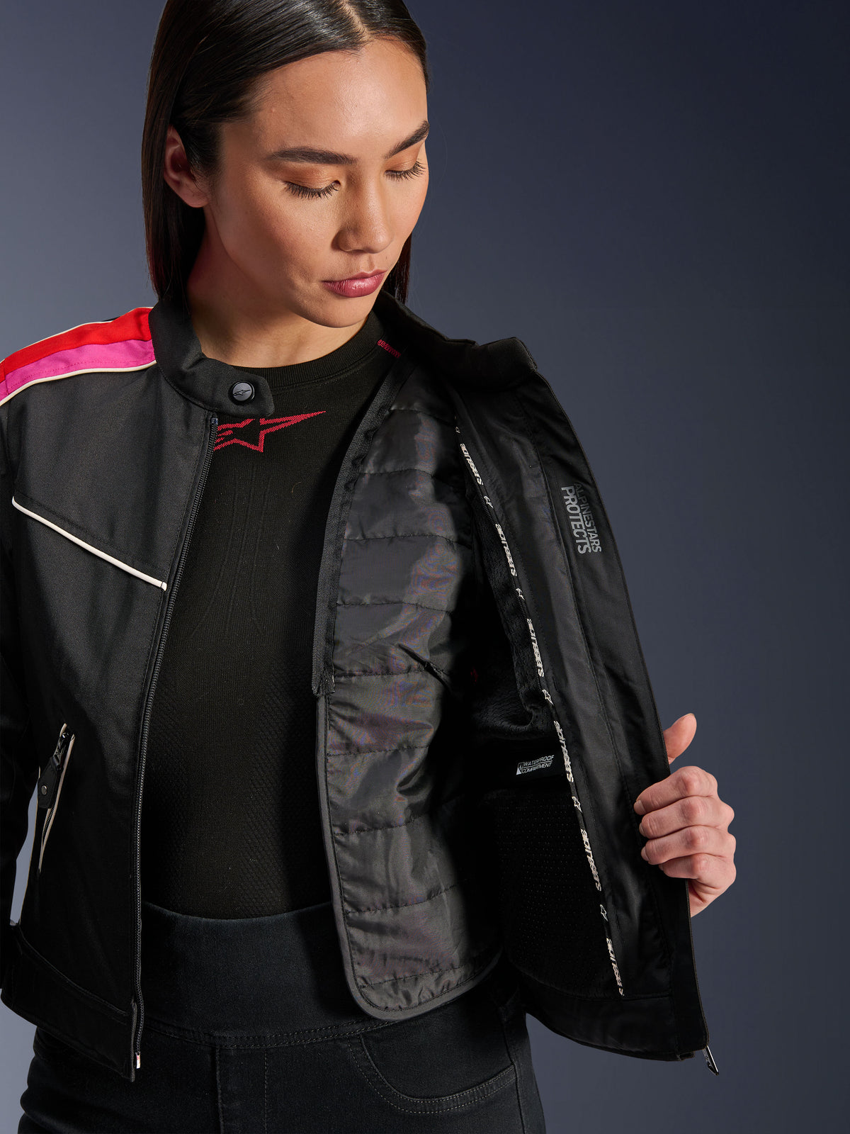 Veste Alpinestars Stella T-Dyno WR, veste de moto en textile, noir rouge vif fuchsia, ouverte pour montrer le gilet thermique matelassé interne et la poche imperméable, coupe biker d'inspiration vintage pour femme