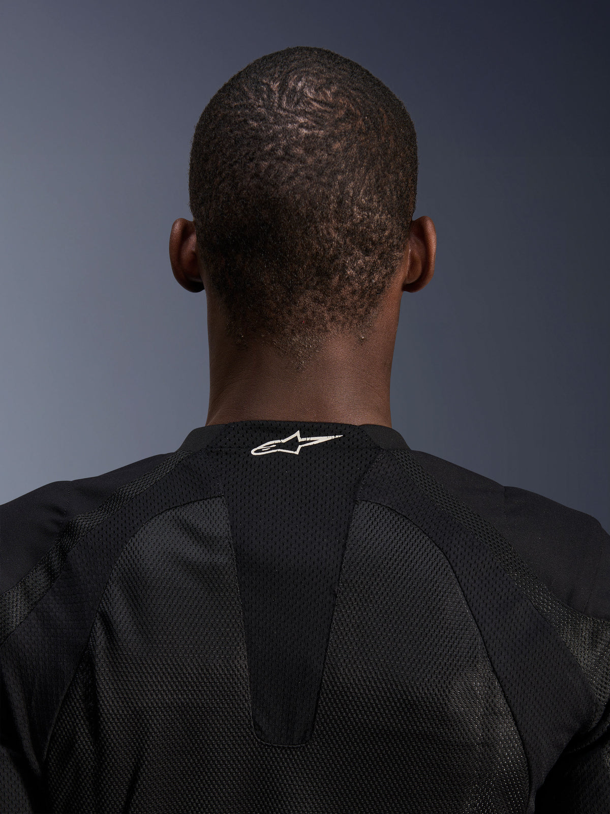 Veste Alpinestars Troop-Air, veste de moto pour homme en maille technique noire, détail du logo blanc sur l'arrière du col.