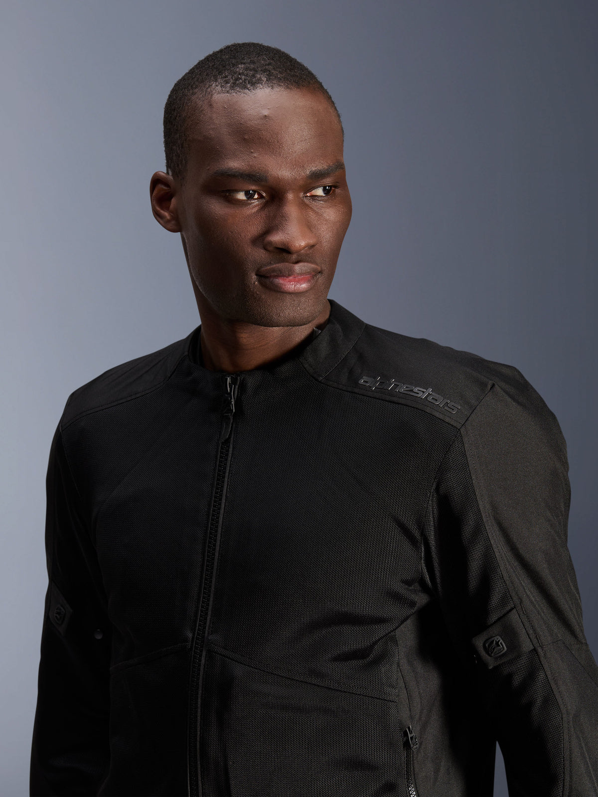 Veste Alpinestars C-1 Air, noire, veste de moto urbaine avec panneaux en maille technique, portée par un mannequin, arborant un logo Alpinestars discret par transfert de chaleur sur l'épaule, conçue pour une circulation de l'air optimale et un confort léger par temps chaud