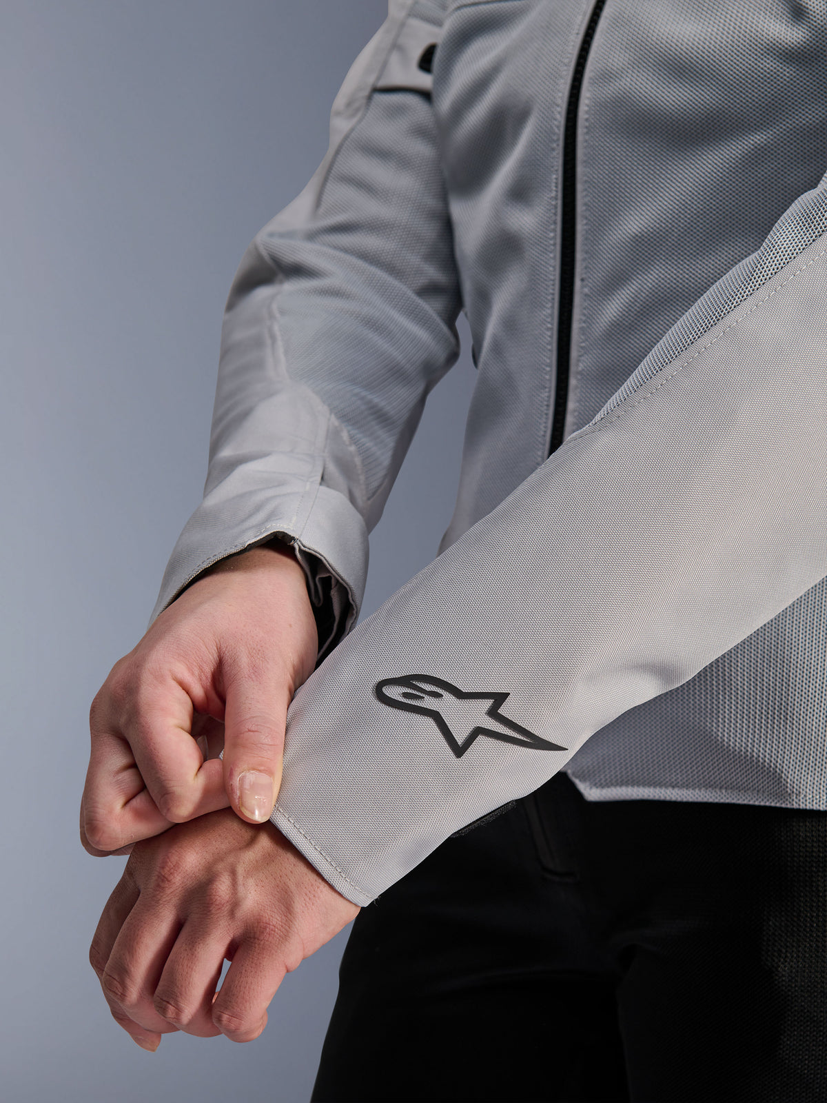 Close-up of Alpinestars Stella C-1 Air Jacket in Silver, featuring technical mesh construction and a black Alpinestars logo on the left sleeve, urban motorcycle jacket for women with reflective branding.