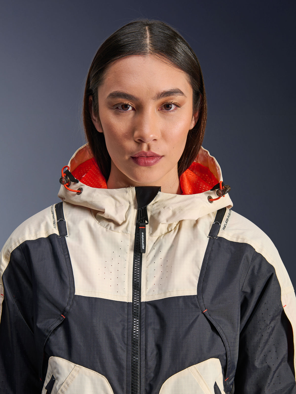Veste Alpinestars Molly Air, veste de moto en textile pour femme, coloris Black Almond, vue rapprochée de face d'un mannequin portant la veste, design à empiècements crème et noir, capuche avec doublure en maille orange vif, détails perforés au laser sur la poitrine