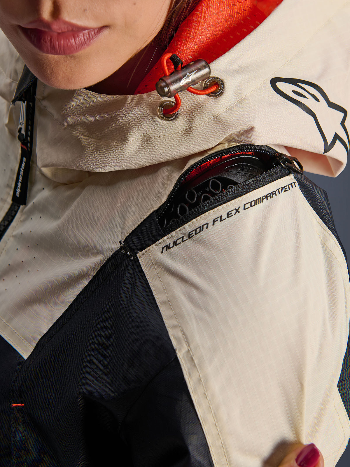 Veste Alpinestars Molly Air, veste de moto pour femme, Black Almond, vue rapprochée de l'épaule montrant la fermeture éclair du compartiment Nucleon Flex, le tissu ripstop et la doublure en maille orange à l'intérieur de la capuche