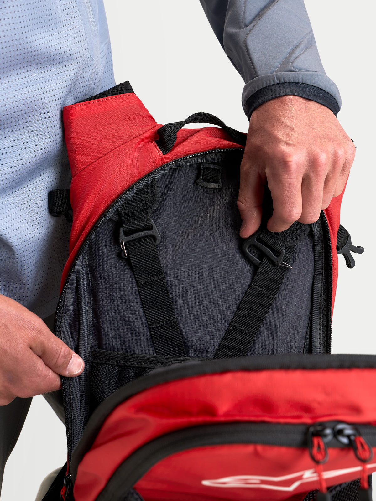 Sac à dos AT-9 Alpinestars, sac à dos de motocross noir et rouge vif, vue en gros plan sur les compartiments de rangement intérieurs et les sangles de réglage du harnais