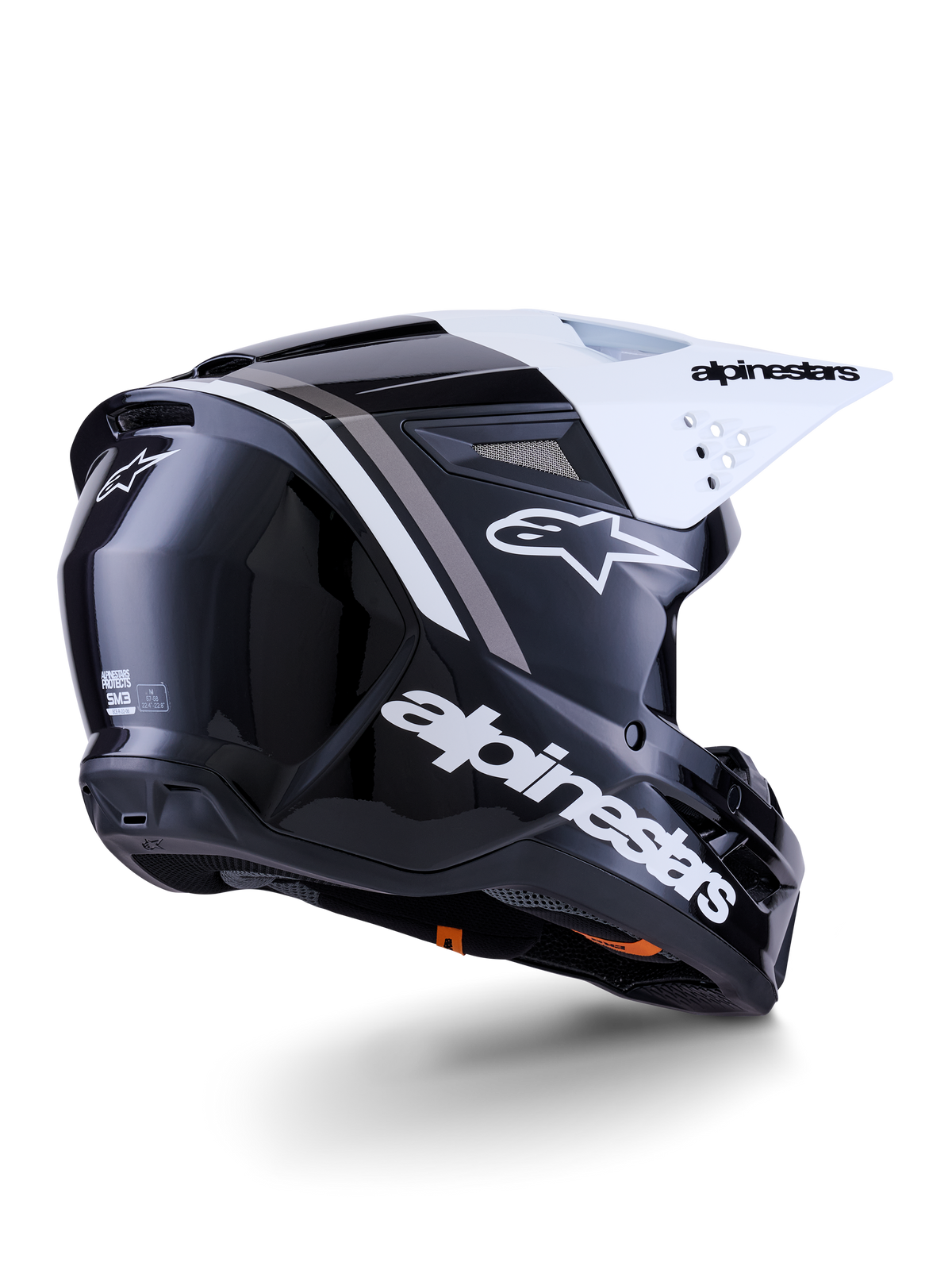Casque Alpinestars S-M3 Radium, casque de motocross, noir, blanc et gris brillant, vue latérale arrière avec visière blanche, logo Alpinestars bien visible sur le côté et à l'arrière, coque aérodynamique épurée avec mesh de ventilation, conçu pour le motocross tout-terrain et l'enduro