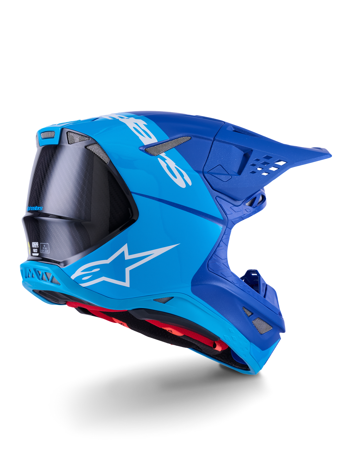 Casque Alpinestars Supertech M10 Flood, casque de motocross, bleu vif et bleu marine avec fibre de carbone noire apparente, profil latéral arrière montrant les orifices de ventilation et le logo blanc, doublure intérieure rouge, conception aérodynamique avancée pour des performances tout-terrain