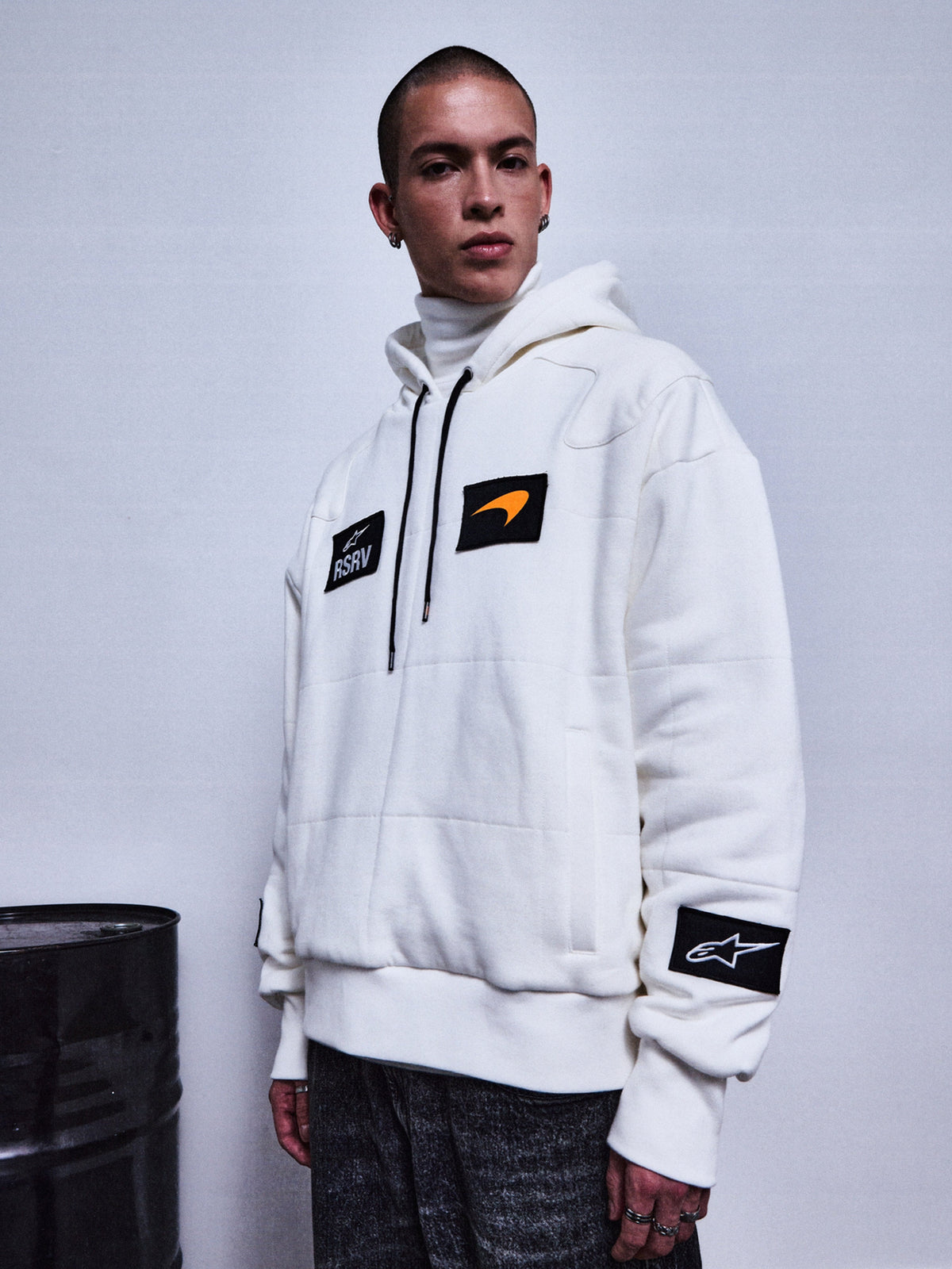 Alpinestars RSRV Rival Hoodie, sweat à capuche blanc avec patchs noirs, swoosh orange, patch étoile sur la manche, col roulé blanc en dessous, style streetwear premium