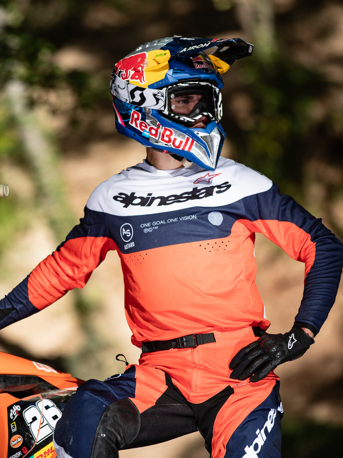 Motocross rider wearing Alpinestars Pro-Dura gear, Navy Hot Orange and White jersey featuring central Alpinestars branding, matching Pro-Dura Pants, Red Bull helmet, and black gloves, coordinated outfit for professional enduro racing