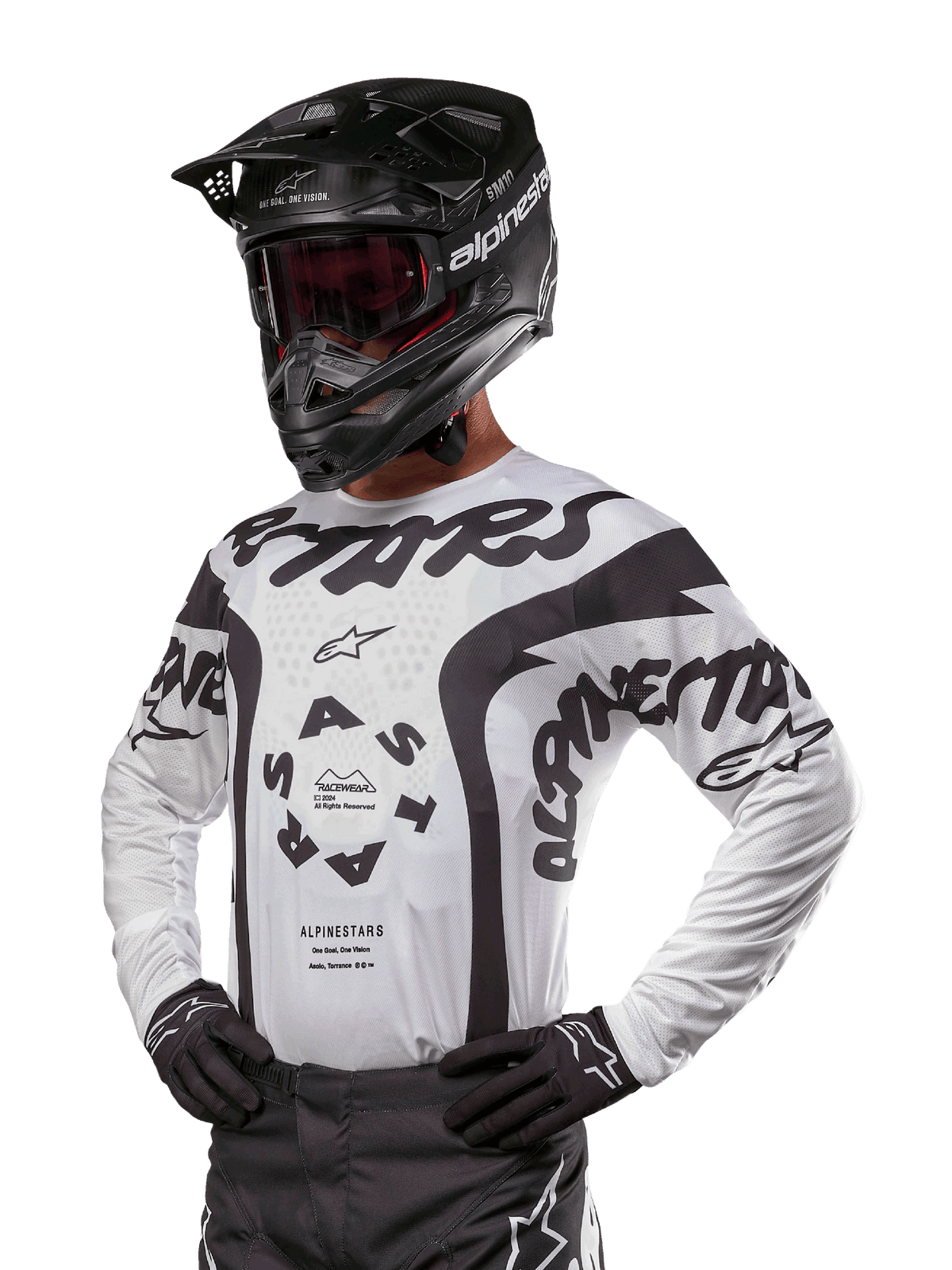 Maillot Alpinestars Racer Hana 2024, maillot de course de motocross, blanc et noir, graphismes audacieux avec marquages Alpinestars et Astars, porté avec casque noir et gants noirs, équipement de motocross tout-terrain haute performance