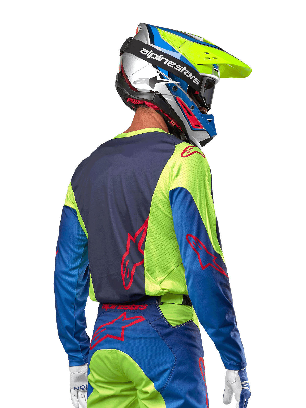 Pilote de motocross portant le maillot Alpinestars Racer Hoen 2024 en Jaune Fluo et Bleu Night Navy, avec un logo étoile rouge au dos, un pantalon de motocross assorti et un casque de course coordonné, vue arrière montrant le design ergonomique pour la performance tout-terrain.