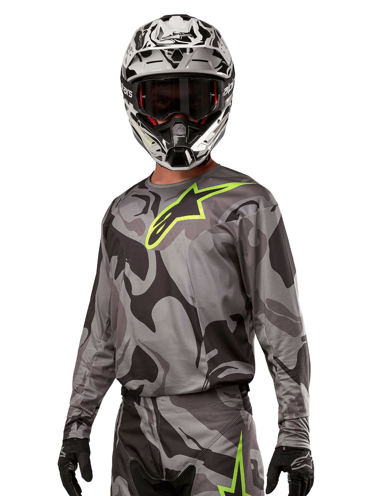 Alpinestars 2024 Racer Tactical Jersey, maillot de motocross, motif camouflage gris avec logo vert fluo, porté avec un casque noir et blanc et des gants noirs, tissu technique évacuant l'humidité pour le tout-terrain