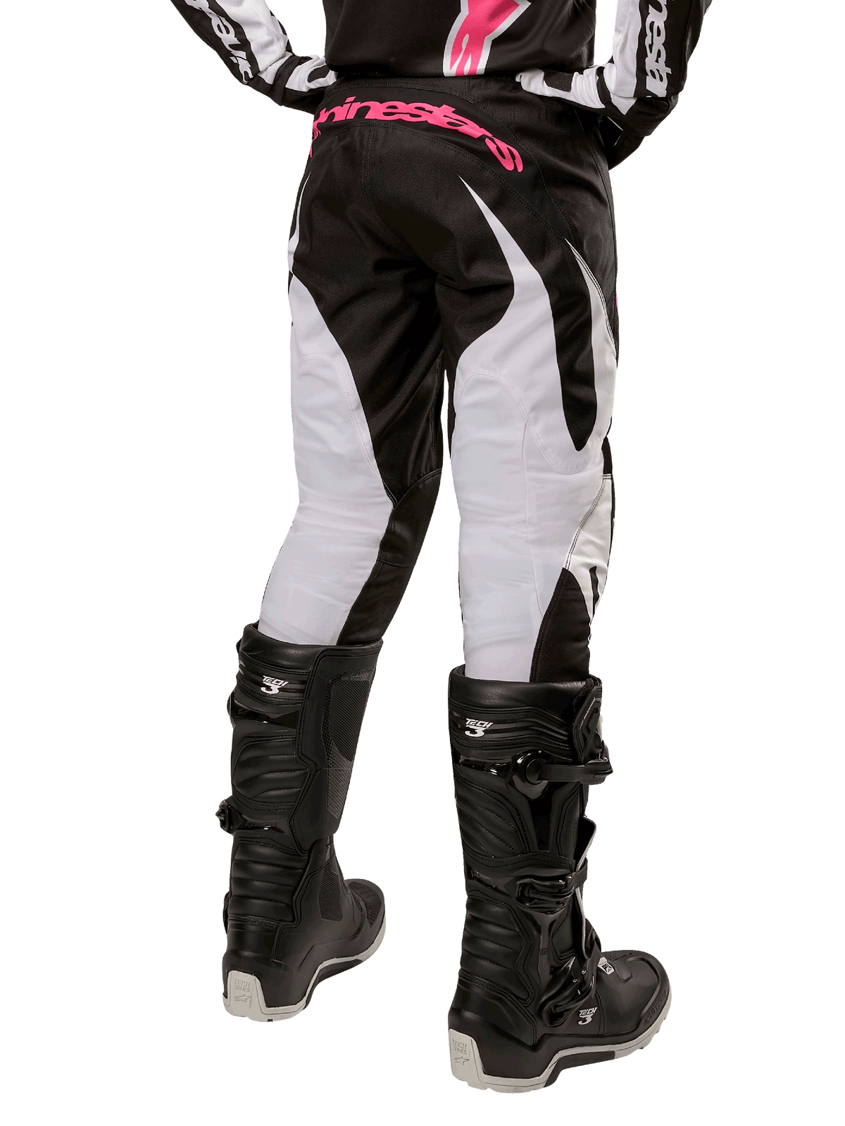 Pantalon Stella Fluid Femme 2024 Alpinestars, pantalon de motocross, noir et blanc, vue arrière montrant des panneaux de jambe blancs et un logo rose sur la taille, porté avec des bottes Tech 3 noires, équipement durable pour la course tout-terrain