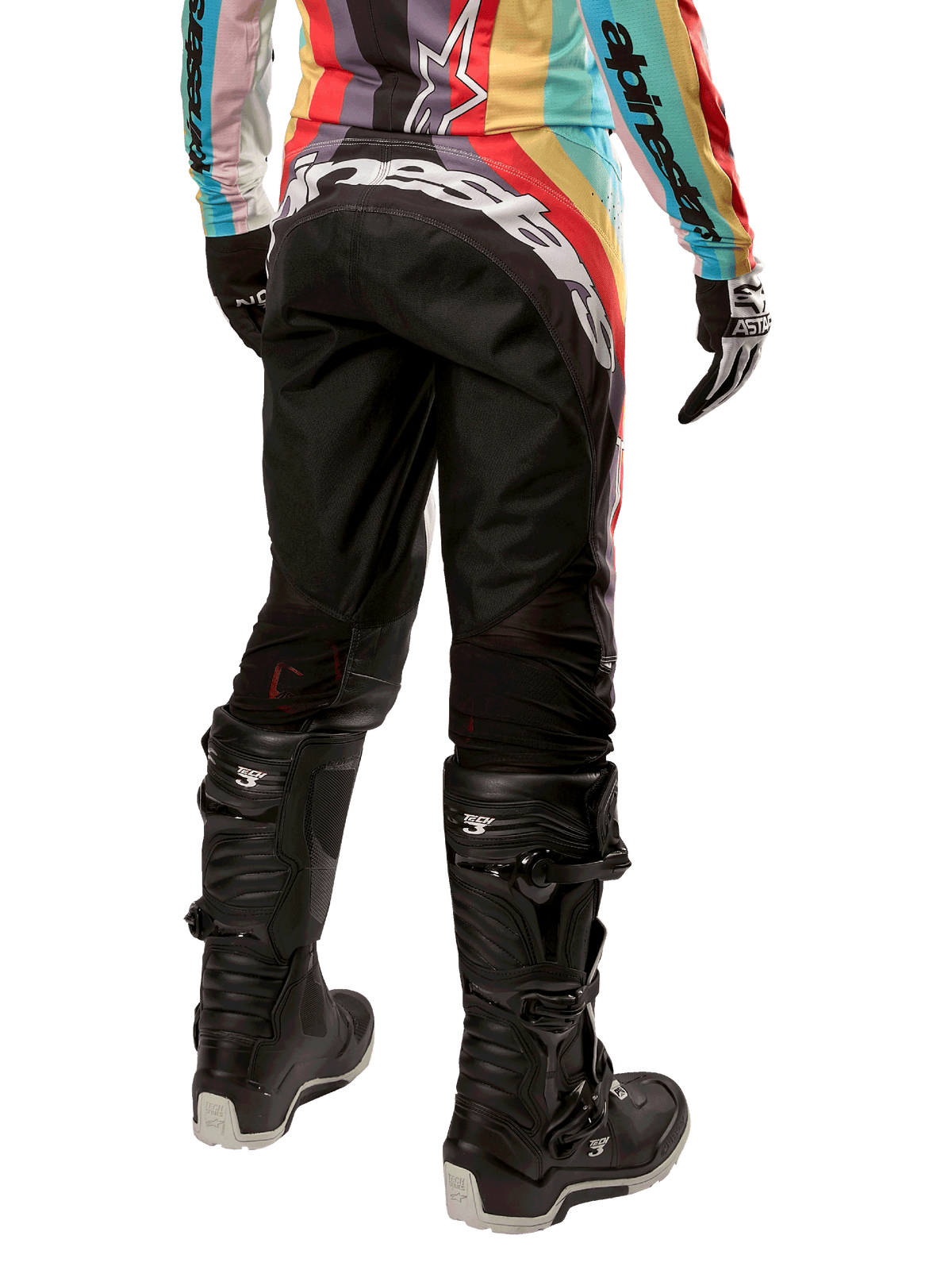 Pantalon femme Alpinestars Stella Techstar 2024, pantalon de motocross, noir multicolore, vue arrière présentant un marquage blanc imposant sur le fessier, porté avec des bottes Tech 3 noires et un maillot multicolore assorti, équipement de course tout-terrain professionnel