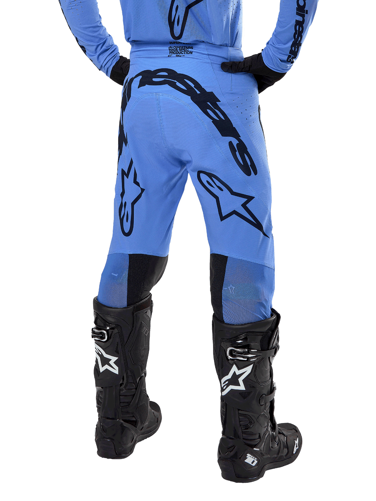 Pantalon Alpinestars Supertech Dade 2024, pantalon de motocross, bleu clair, vue arrière montrant un large marquage noir sur l'assise et les jambes, porté avec des bottes Alpinestars Tech 10 noires, coupe athlétique pour une performance tout-terrain professionnelle.