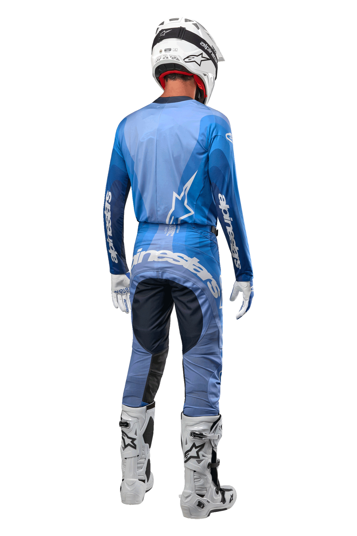 Pilote de motocross vu de dos portant le pantalon Alpinestars Techstar Pneuma 2024 bleu marine et bleu clair, maillot bleu assorti, casque, gants et bottes blancs, avec le marquage Alpinestars sur l'assise et les manches.