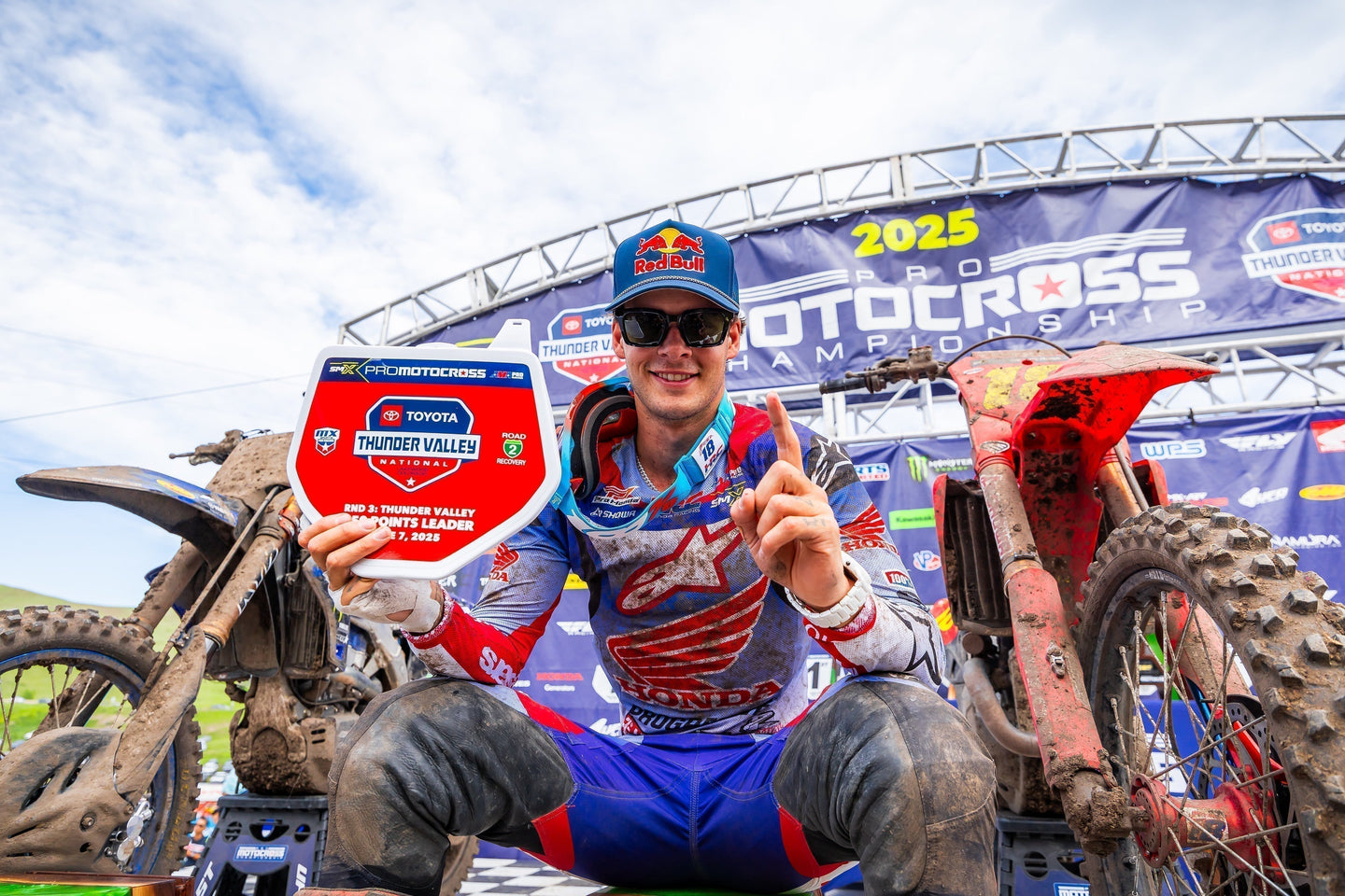 Motocross champion Jett Lawrence celebrating a win wearing an Alpinestars blue and red jersey.