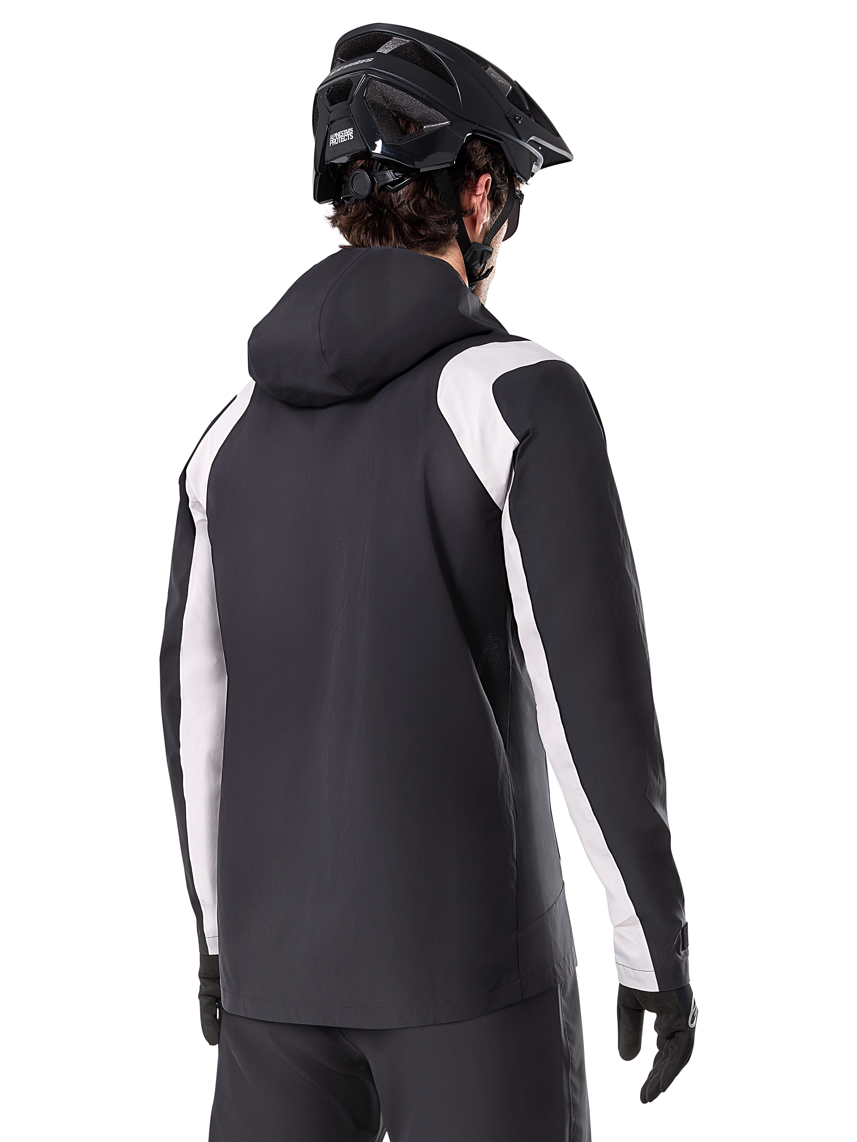Veste de pluie Alpinestars A-Dura, veste de pluie pour VTT, noire avec empiècements blancs sur les manches, vue arrière d'un cycliste portant un casque de VTT noir et des gants, construction technique imperméable à 2,5 couches, équipement de VTT