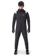Veste de pluie Alpinestars A-Dura, veste de pluie de VTT, noire avec accents blancs aux épaules et logo blanc sur la poitrine, portée avec pantalon noir, casque noir, lunettes de soleil et gants, équipement de VTT coordonné pour le temps pluvieux