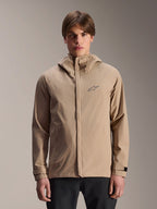 Veste de pluie Alpinestars A-Dura, veste de pluie de VTT à capuche marron clair, portée par un mannequin, dotée d'un petit logo sur la poitrine, de poignets réglables et d'une fermeture éclair frontale dissimulée, équipement de cyclisme imperméable
