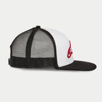 Casquette Trucker Alpinestars Corp, blanc et noir, vue de profil montrant le panneau avant blanc avec logo rouge brodé en 3D, visière plate noire et arrière en maille, style streetwear décontracté motorsport