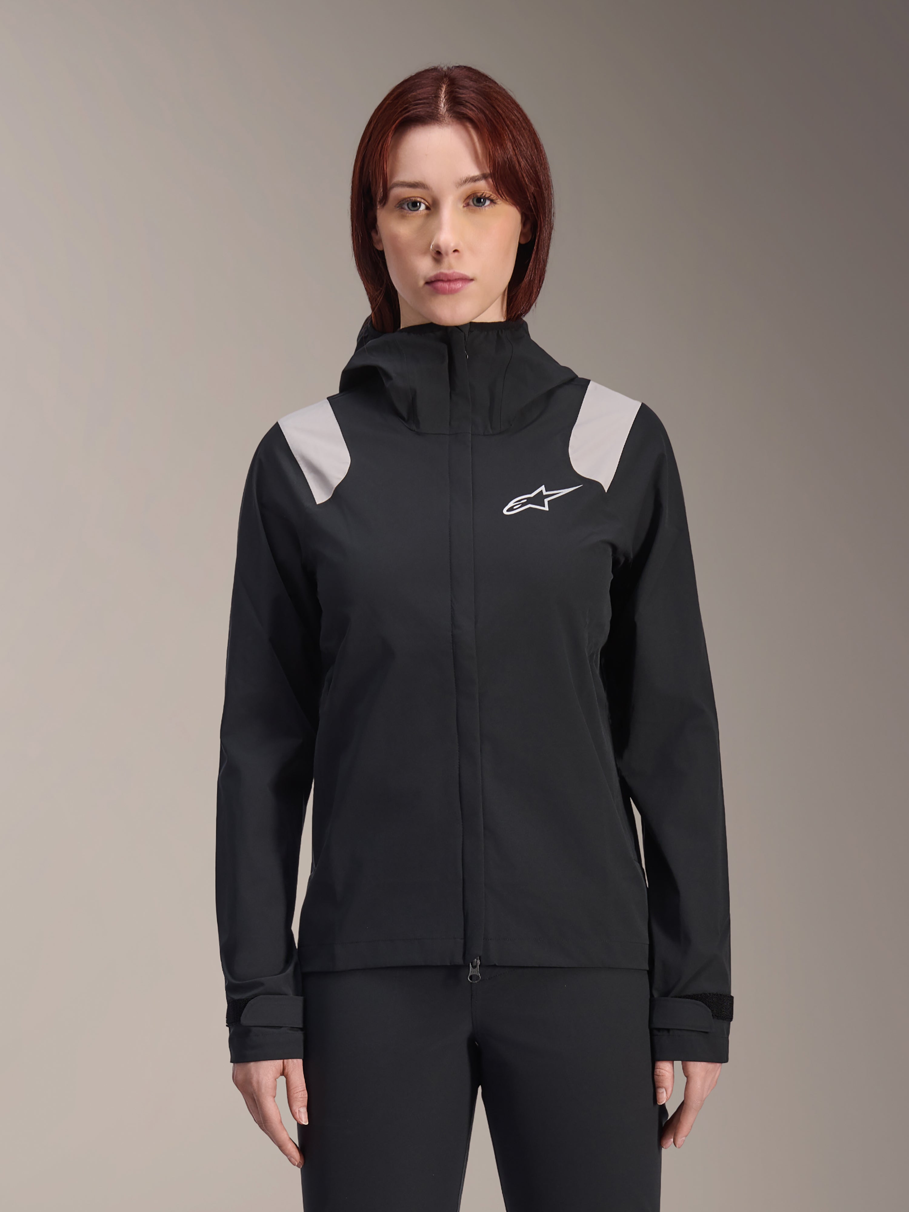 Alpinestars Stella A-Dura Rain Jacket, Women's Cycling Rain Jacket, Black with light gray shoulder panels, hooded technical shell with white logo on chest, adjustable Velcro cuffs, professional gear for MTB and wet weather riding