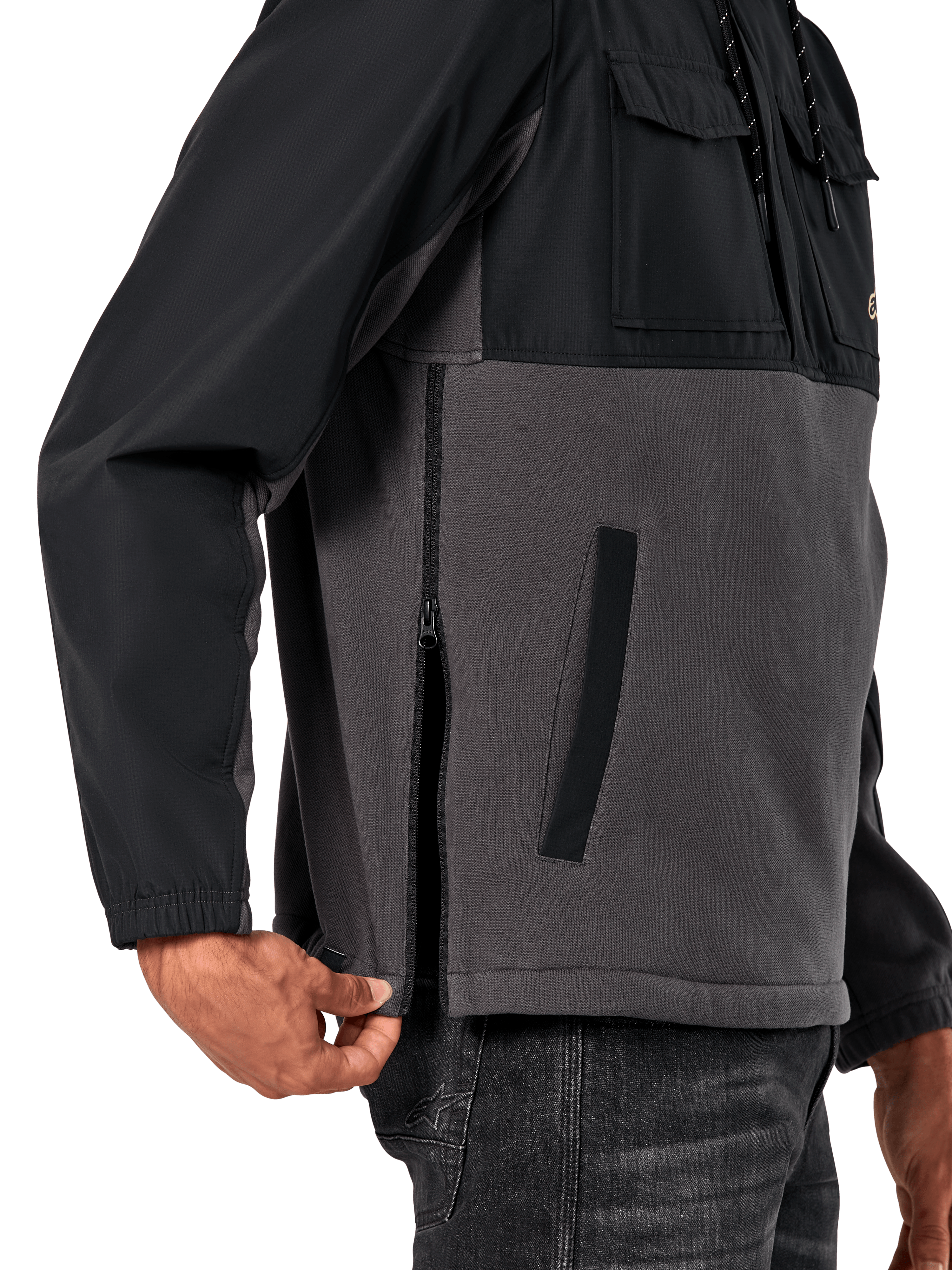 Veste Hybride Juncture Alpinestars en Noir Gunmetal, vue latérale détaillée mettant en évidence la fermeture éclair latérale et la poche passepoilée inférieure, conception multi-matières avec polaire de toile grise et empiècements ripstop noirs, streetwear décontracté inspiré du sport automobile