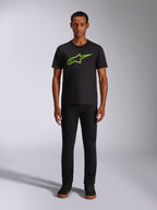 T-shirt Alpinestars Ageless 2.0 CSF, t-shirt à manches courtes, noir avec logo vert vif, porté par un mannequin avec un pantalon noir, design décontracté inspiré des sports mécaniques
