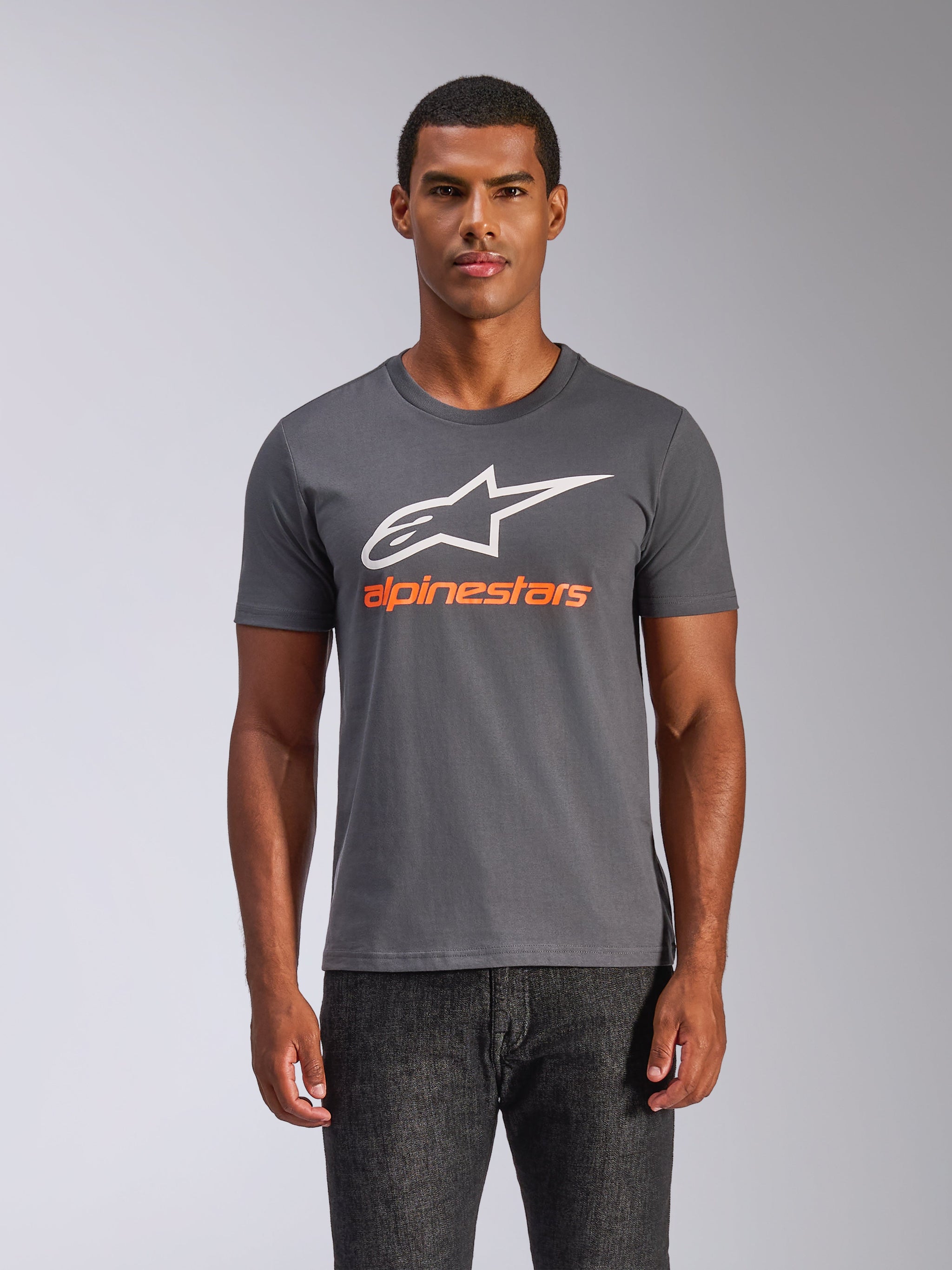 T-shirt Alpinestars Always 2.0 CSF, t-shirt à manches courtes, gris anthracite, grand logo A-star blanc avec inscription Alpinestars orange, porté par un homme, streetwear décontracté motorsport
